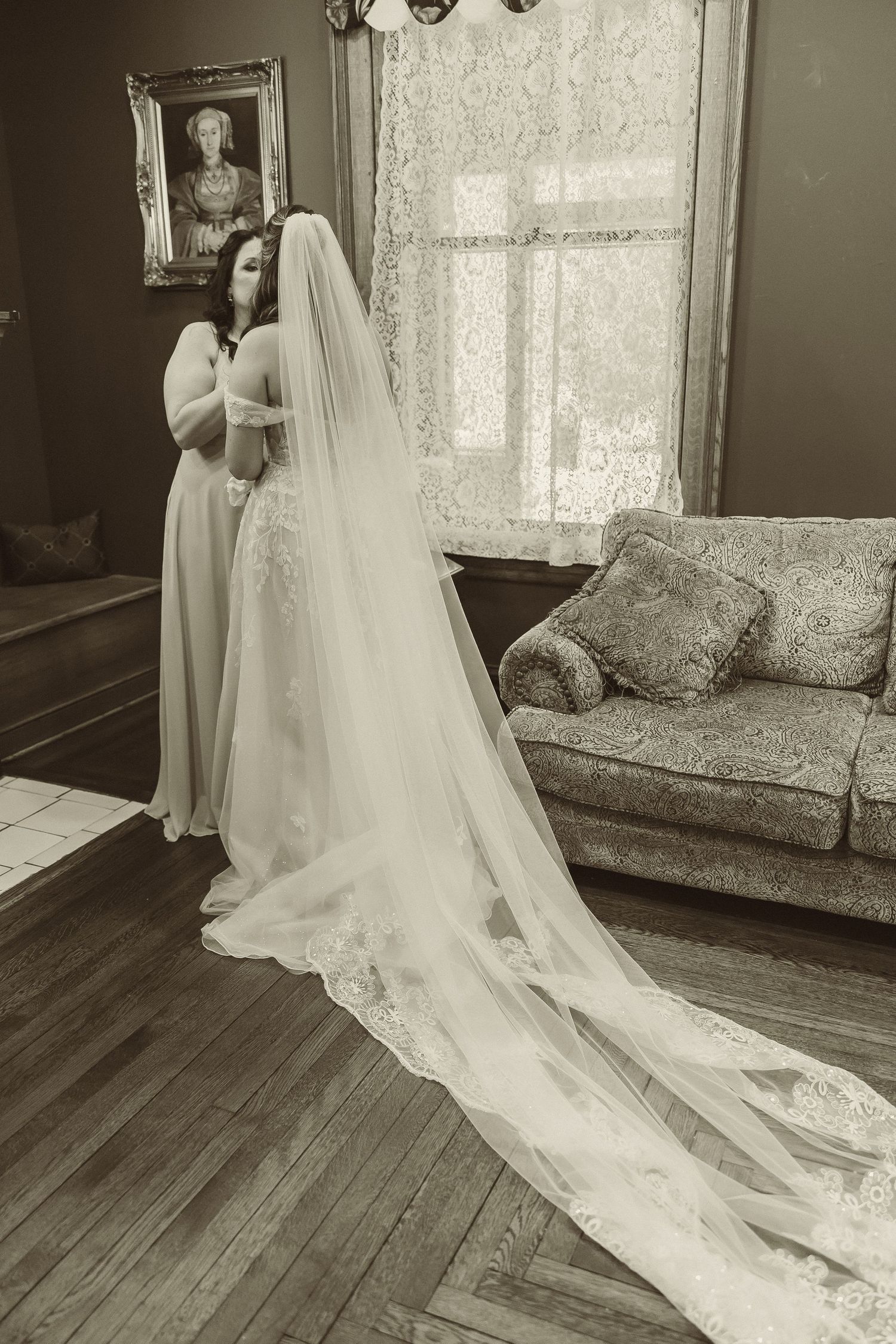 Classic black and white photo showing long wedding veil trailing across vintage hardwood floors.