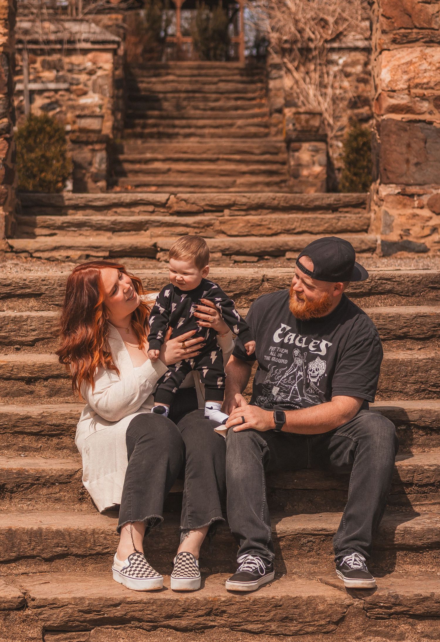 Family sitting on rustic stone staircase sharing playful moment.