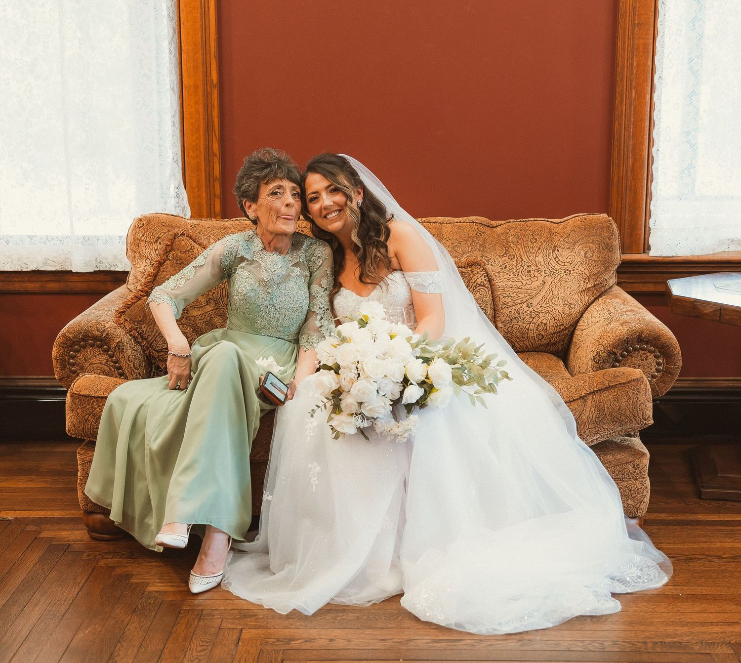 Elegant wedding scene on vintage brown couch with soft natural lighting.