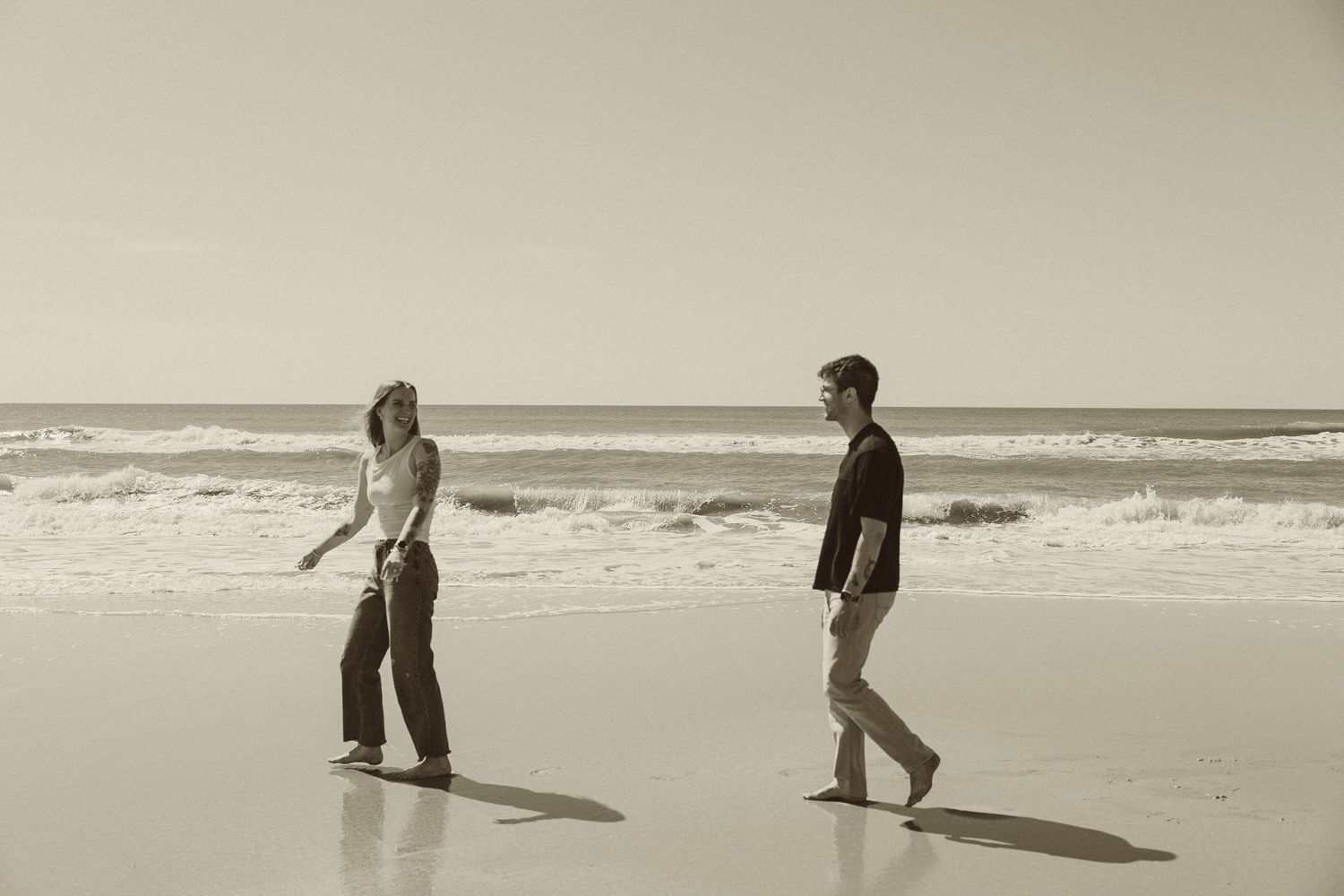 A series of vintage-style sepia photographs showing figures walking along a beach with waves and shadows cast on the sand.
