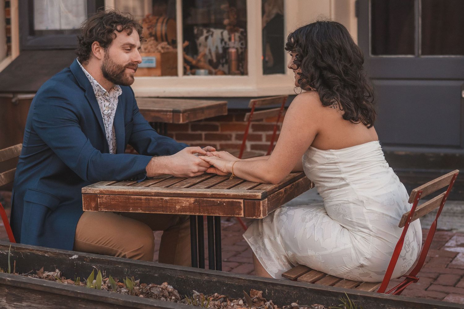 A couple sits together at an outdoor table having an intimate conversation.