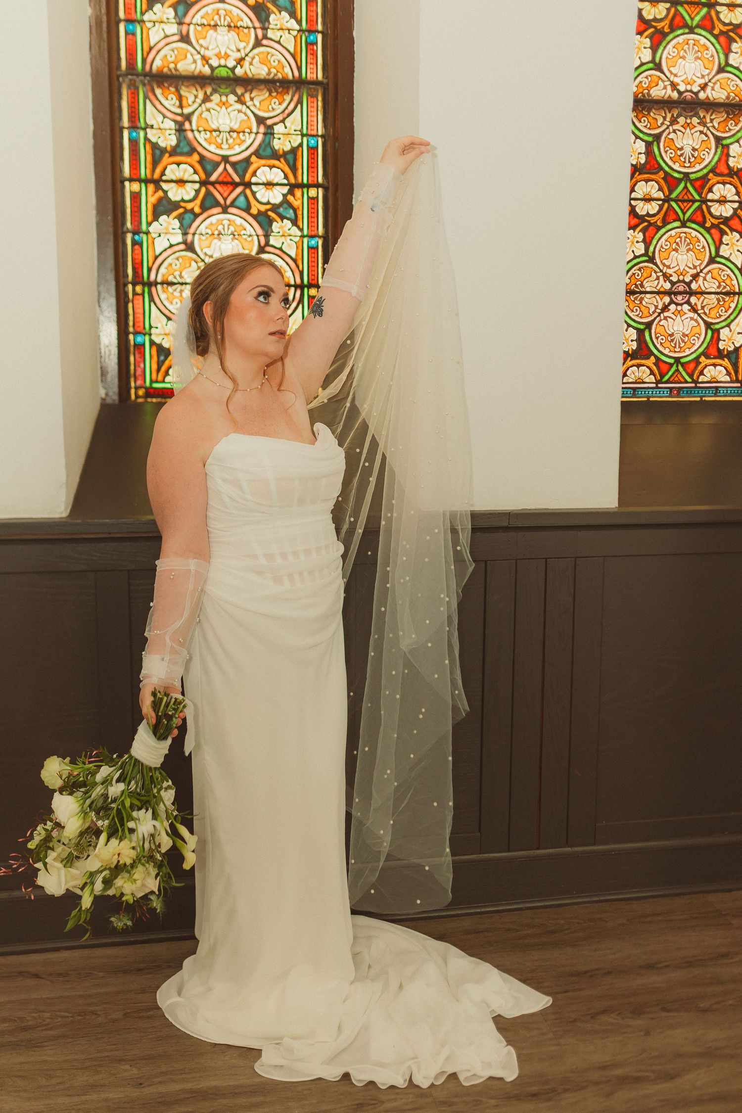 A wedding photoshoot in a church with beautiful stained glass windows in the background.