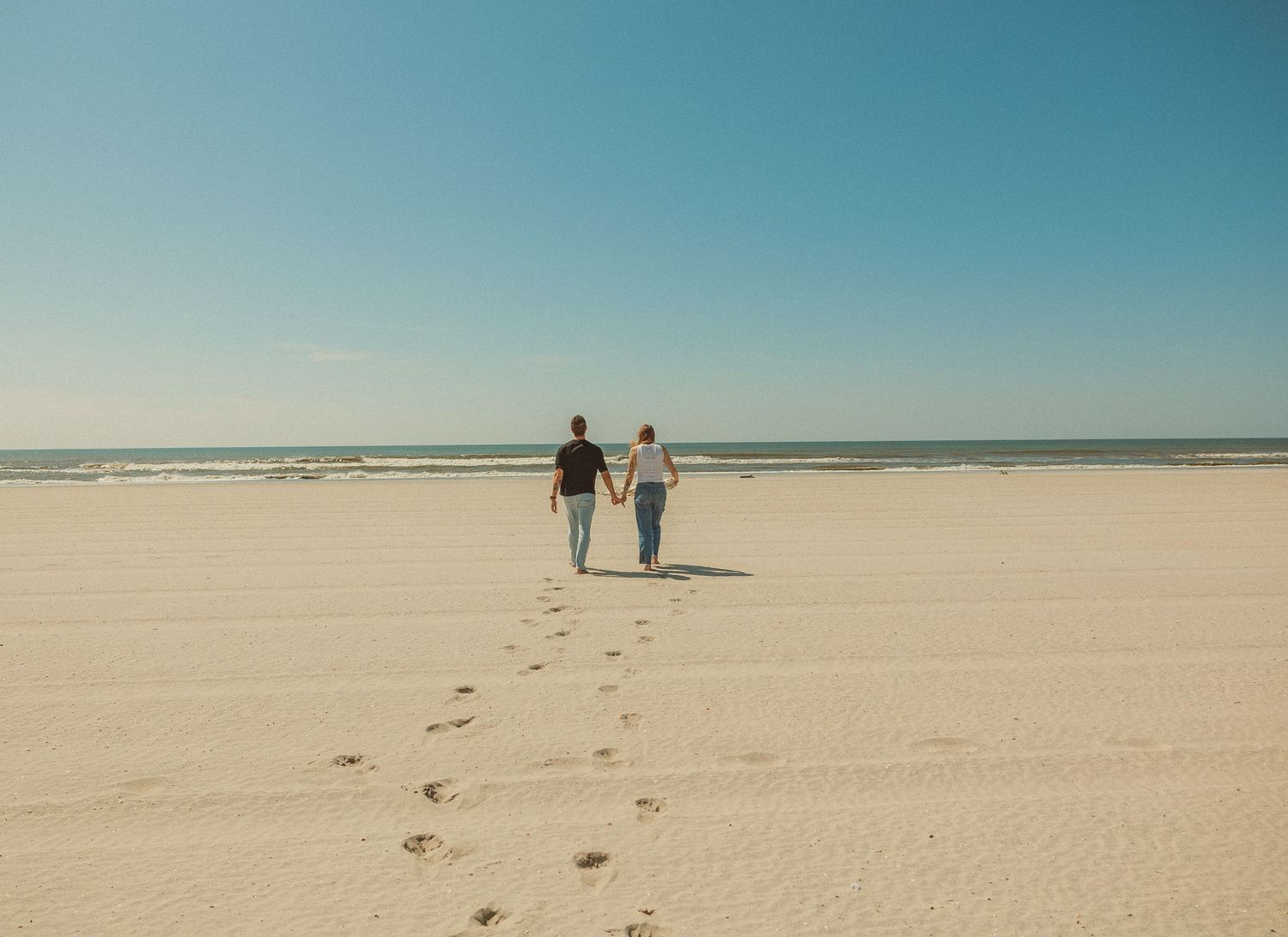 Overlapping views of a couple walking along a pristine white sandy beach with blue ocean waters in the distance.