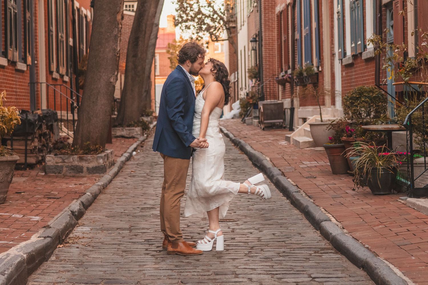 A couple enjoys a romantic moment on a charming brick-paved street.