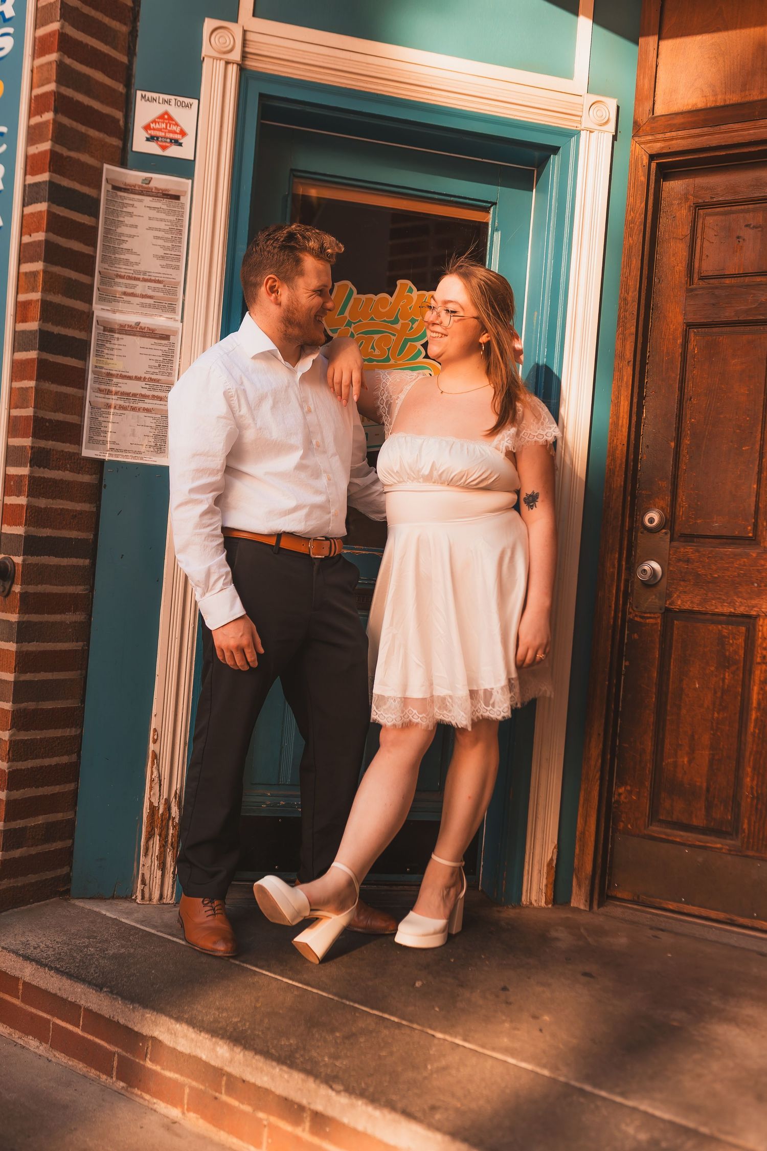 A couple shares a tender moment in a turquoise doorframe during a sunset photoshoot.