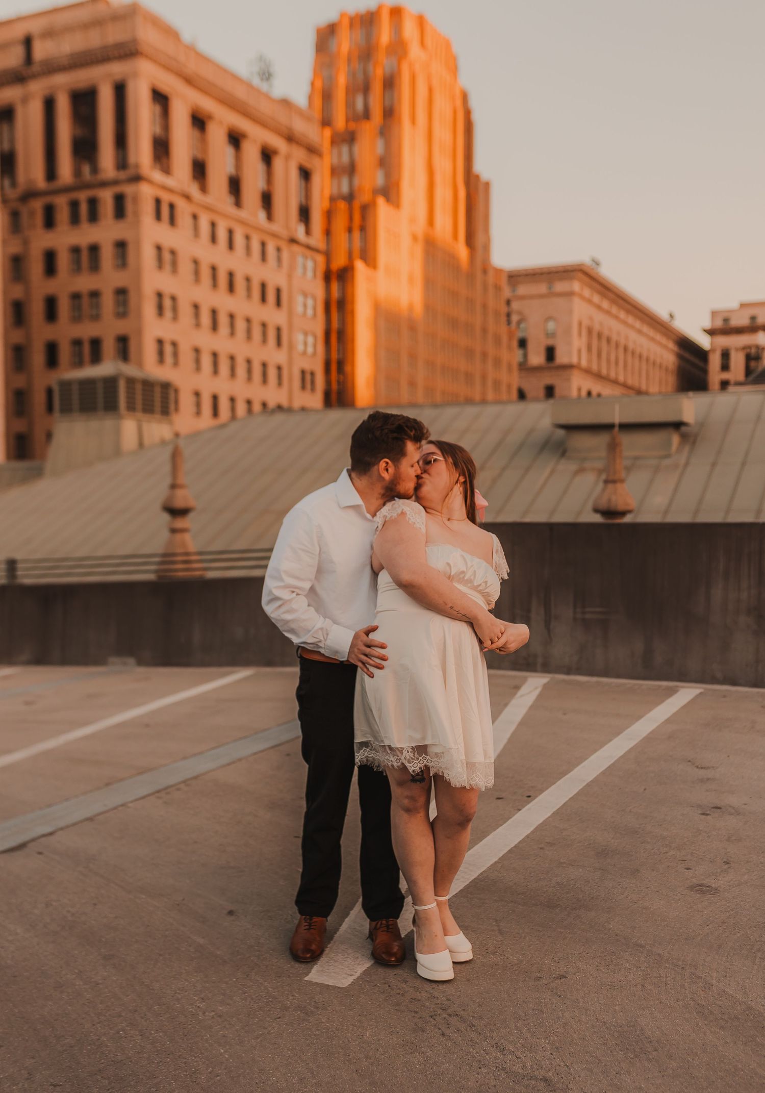 Romantic sunset embrace on urban rooftop with art deco buildings in background.