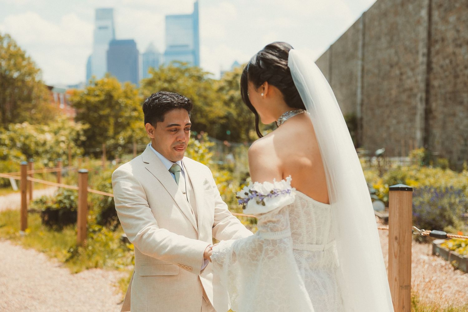 A storybook wedding moment captured outdoors with city skyscrapers in the background on a sunny autumn day.