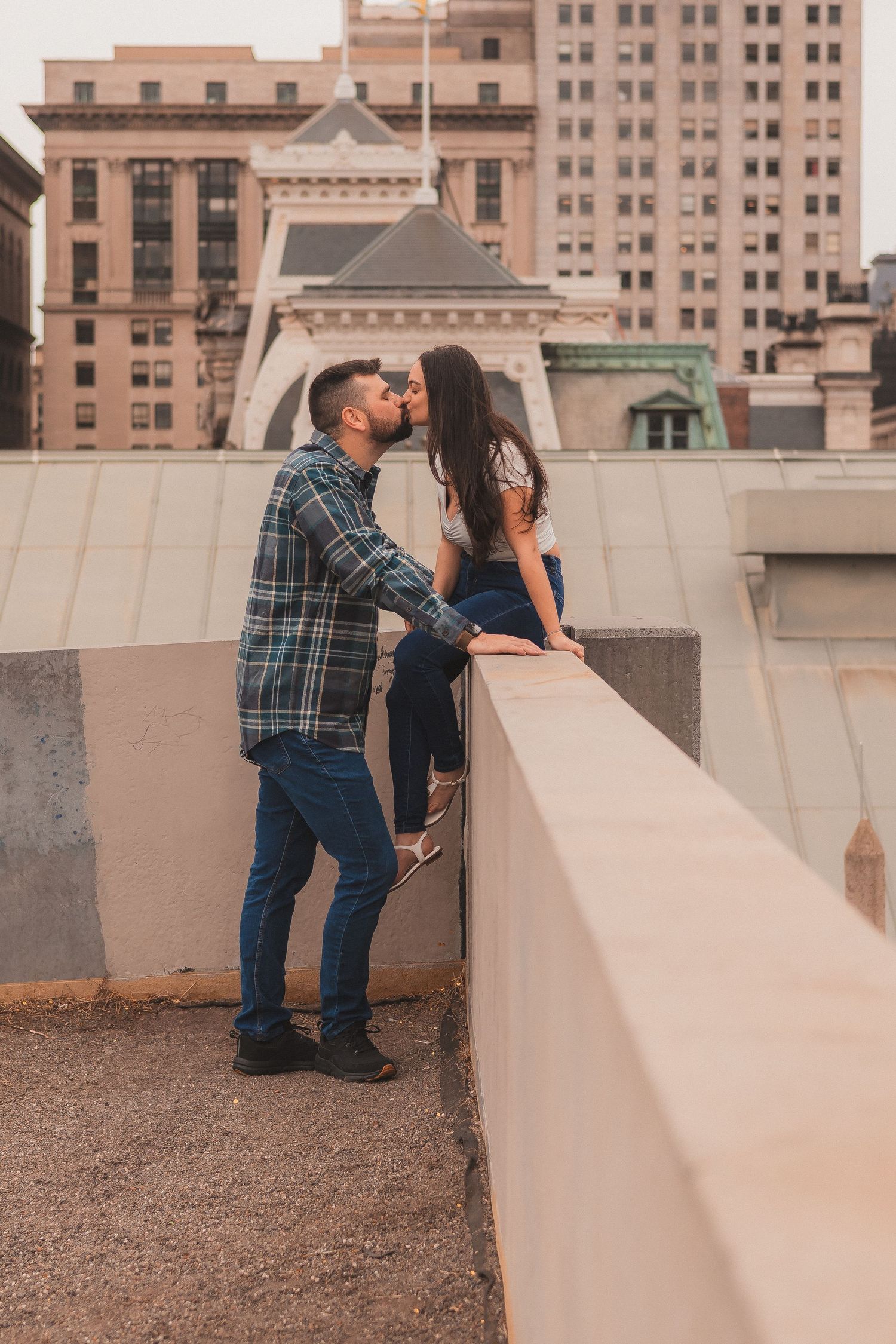 A couple enjoying a romantic moment on a city rooftop with architecture in the background.