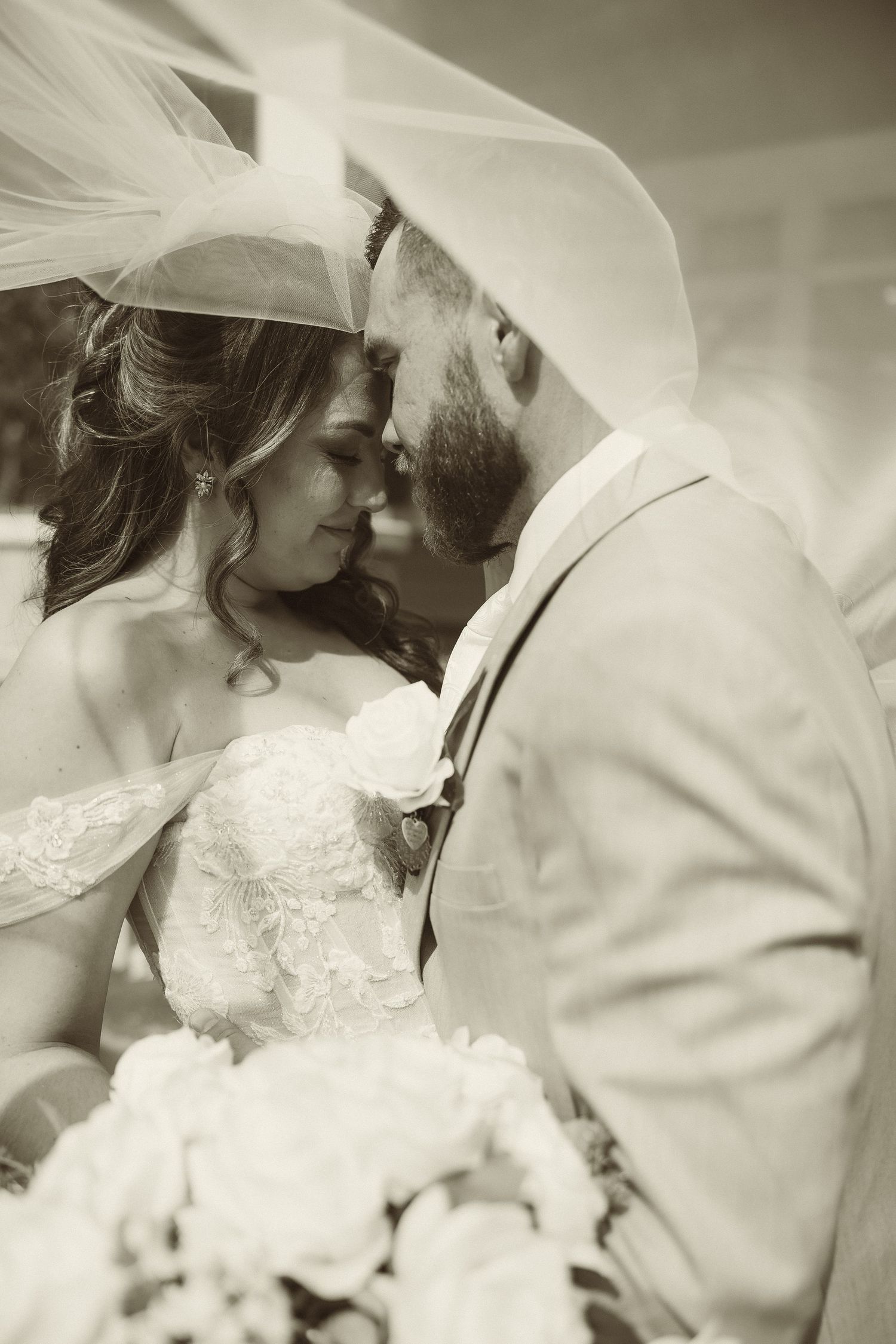 A romantic sepia-toned wedding portrait with the couple sharing a tender moment.