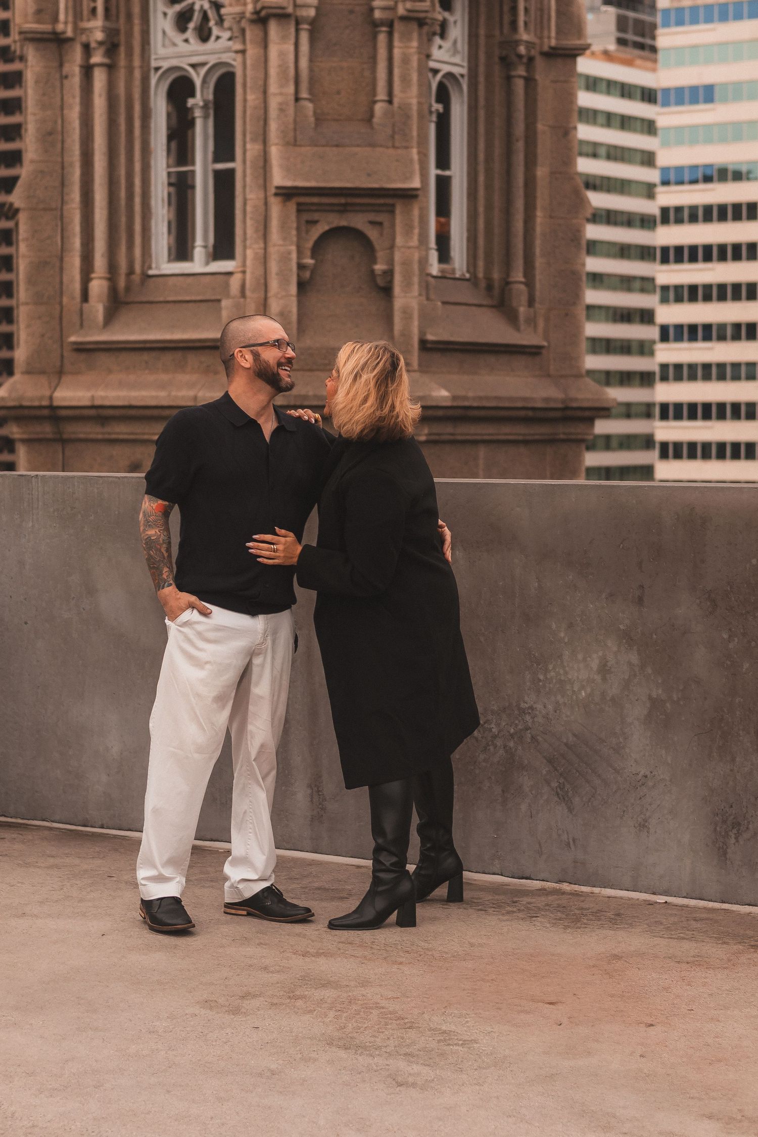 A couple sharing an intimate moment against a Gothic church building and modern city backdrop.