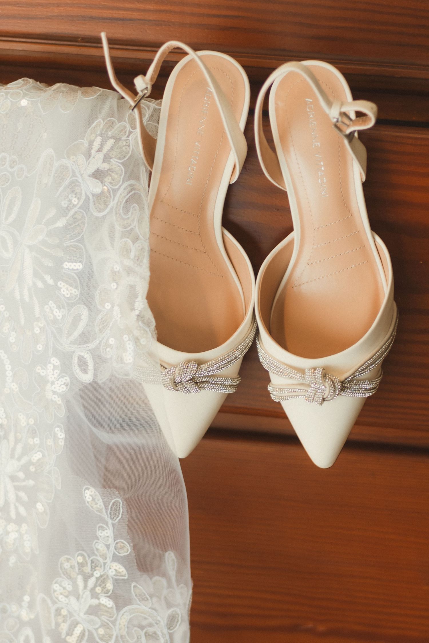 White bridal shoes with decorative details displayed next to delicate lace fabric.