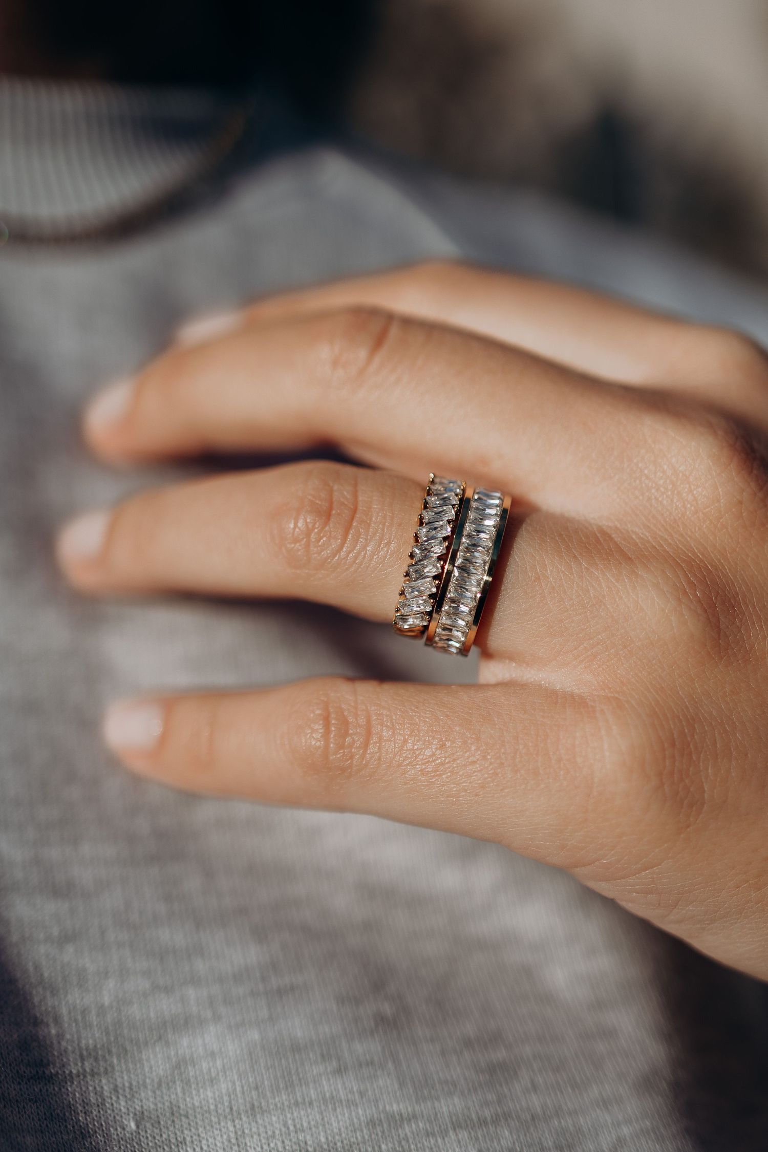 Multiple views of a delicate diamond wedding band with a distinctive two-row design glinting on a hand against a gray background.