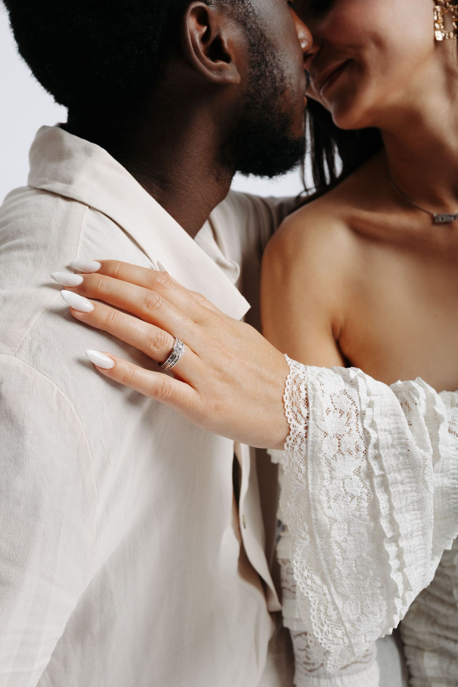 A series of closeup shots showing embracing couple with engagement ring and lace sleeve details in white wedding attire.