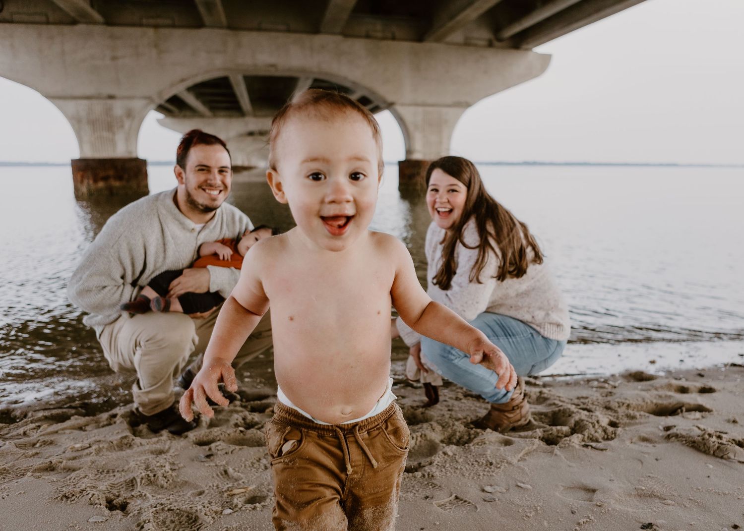family under bridge playing in water