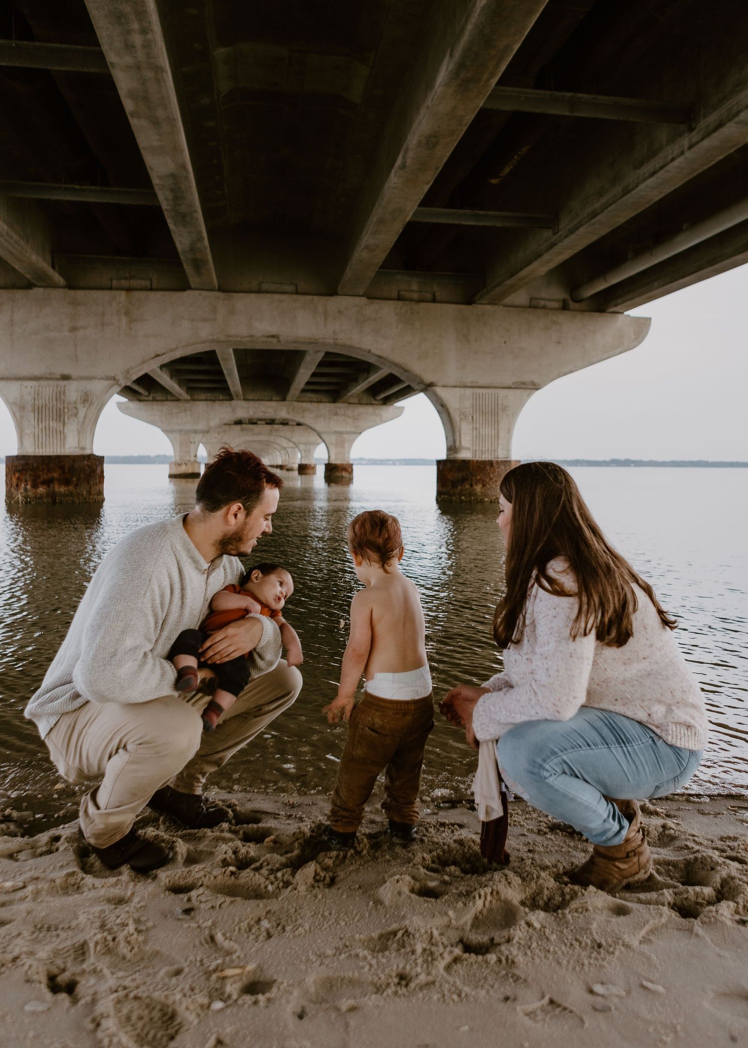 family under bridee playing in water
