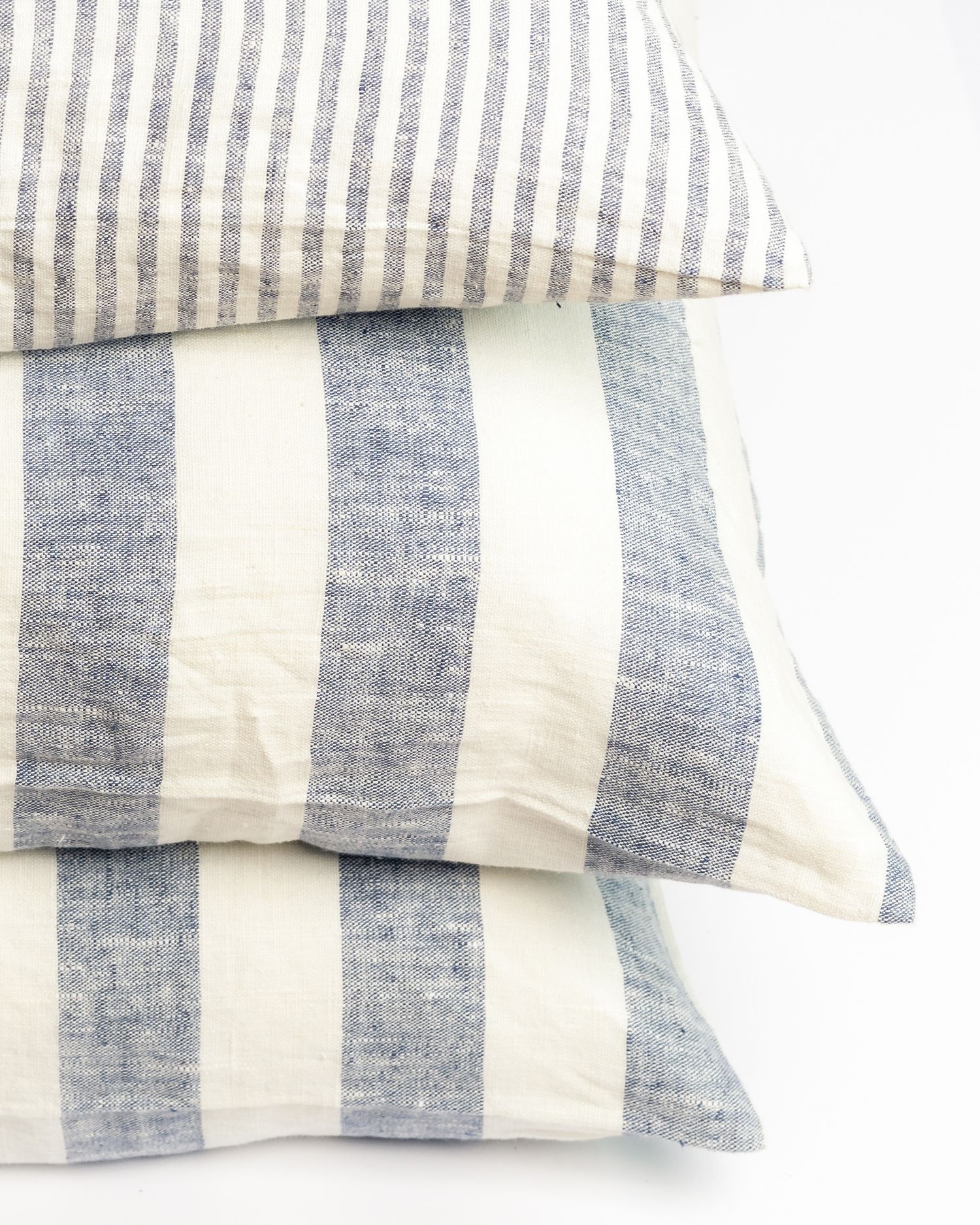 Decorative pillows featuring blue and white stripes in varying widths, product photography by Portland Maine photographer Ang Foley
