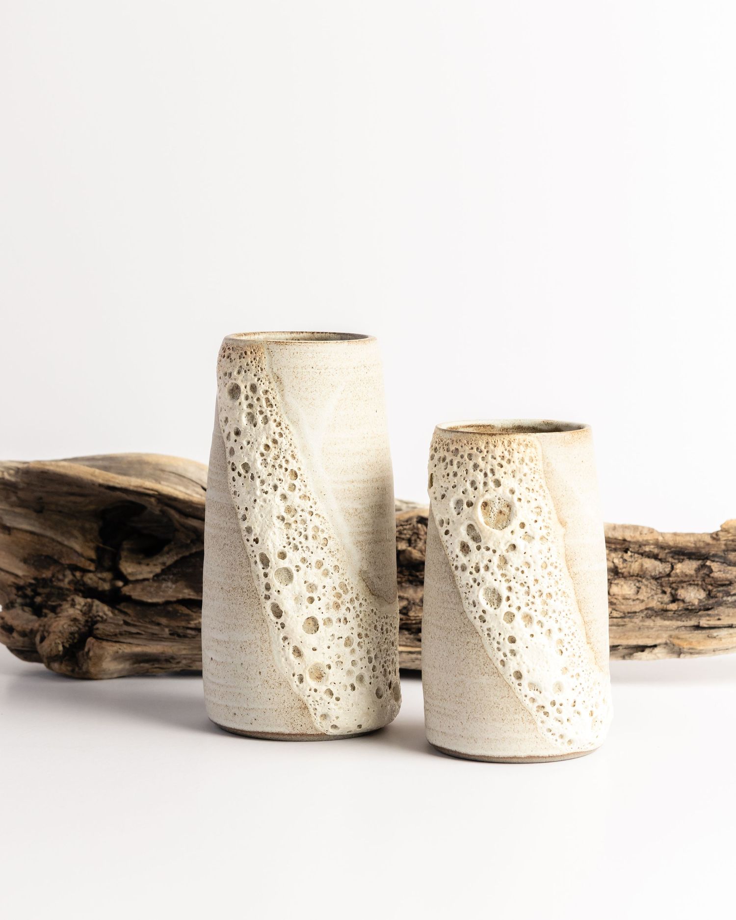 Ceramic vases with organic crater texture detail, displayed with driftwood, product photography by Portland Maine photographer Ang Foley