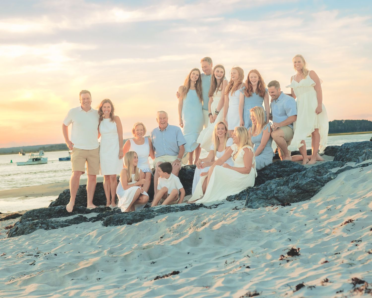 Southern Maine Family Portrait Photographer - Extended family gathered on a beach at sunset wearing coordinated light colored clothing.