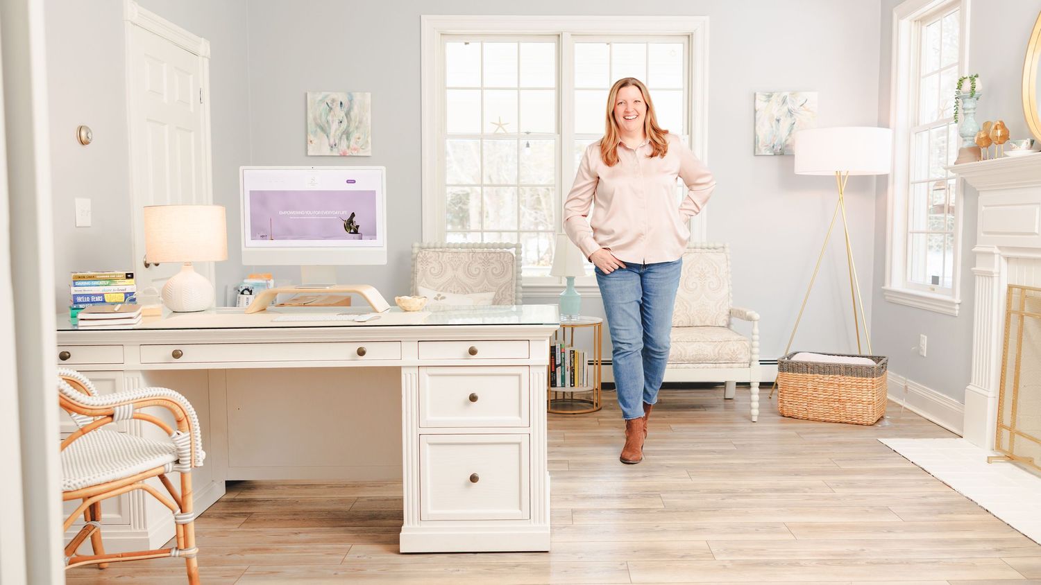 Brand Photography - Small Business owner in bright home office space with white desk, decorative accessories, and coastal-inspired decor.