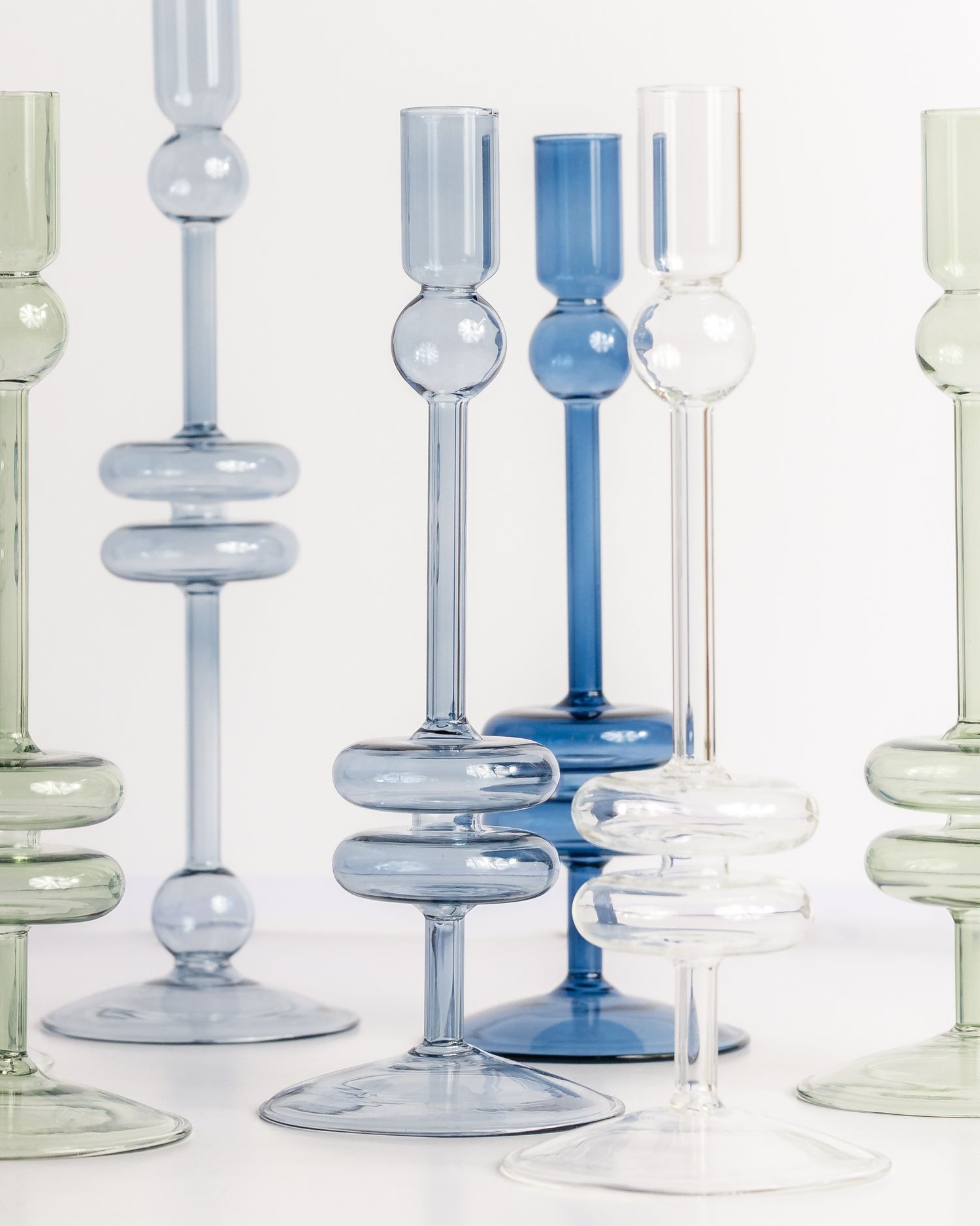 Elegant blue, green, and clear glass taper candleholders of varying heights, product photography by Portland Maine photographer Ang Foley