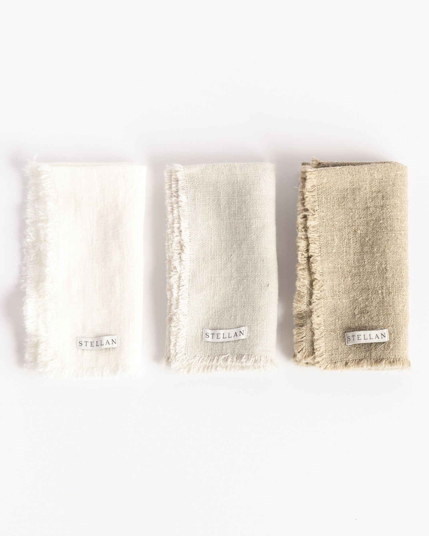 Three Stellan linen napkins in white, cream, and tan with frayed edges, product photography by Portland Maine photographer Ang Foley