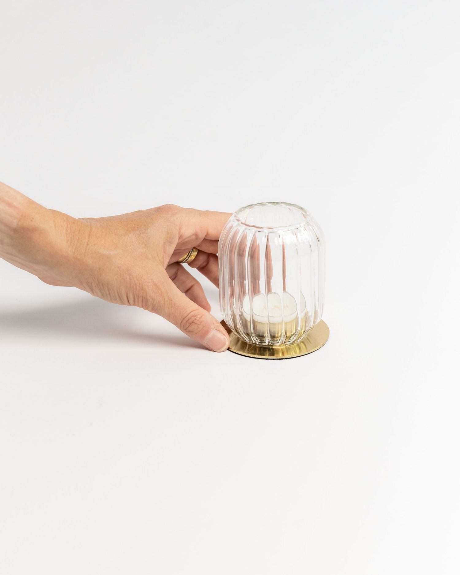 Ribbed glass votive candle holder with a gold brass base on a white background, product photography by Portland Maine photographer Ang Foley