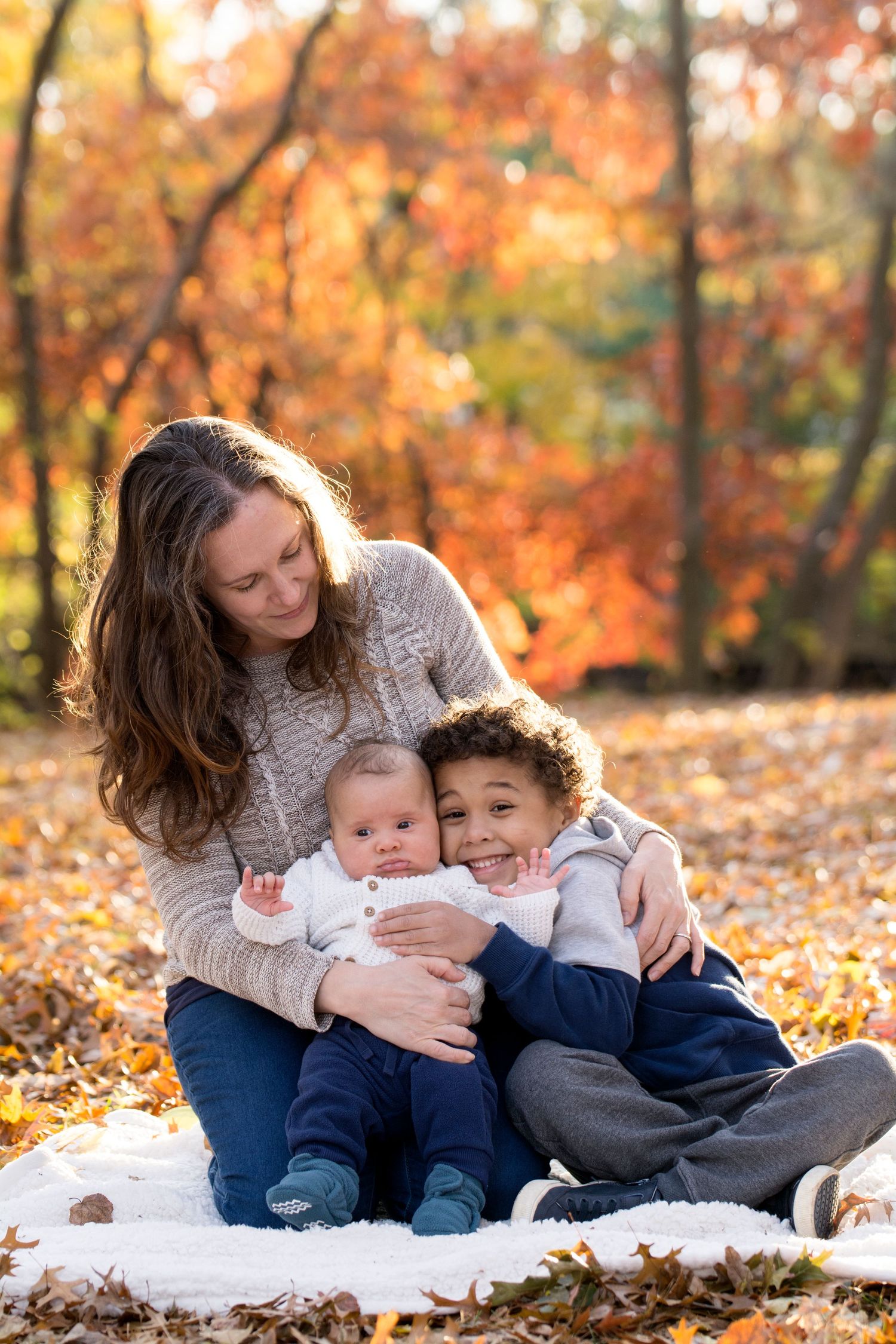 A cozy family moment on a blanket surrounded by vibrant fall foliage.