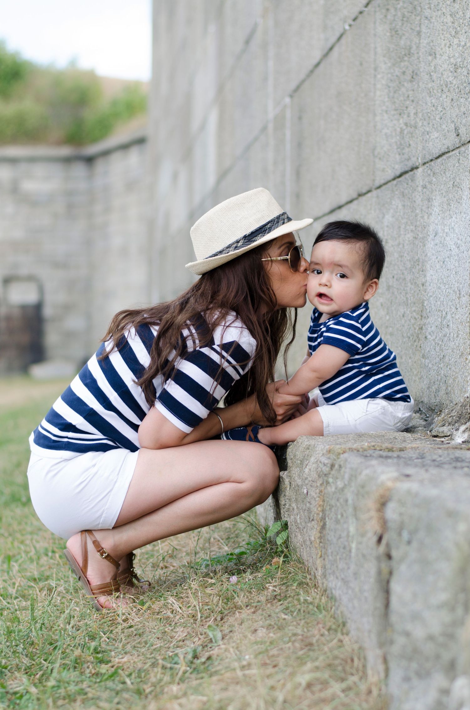 A tender moment captured against a stone wall in matching navy striped outfits.