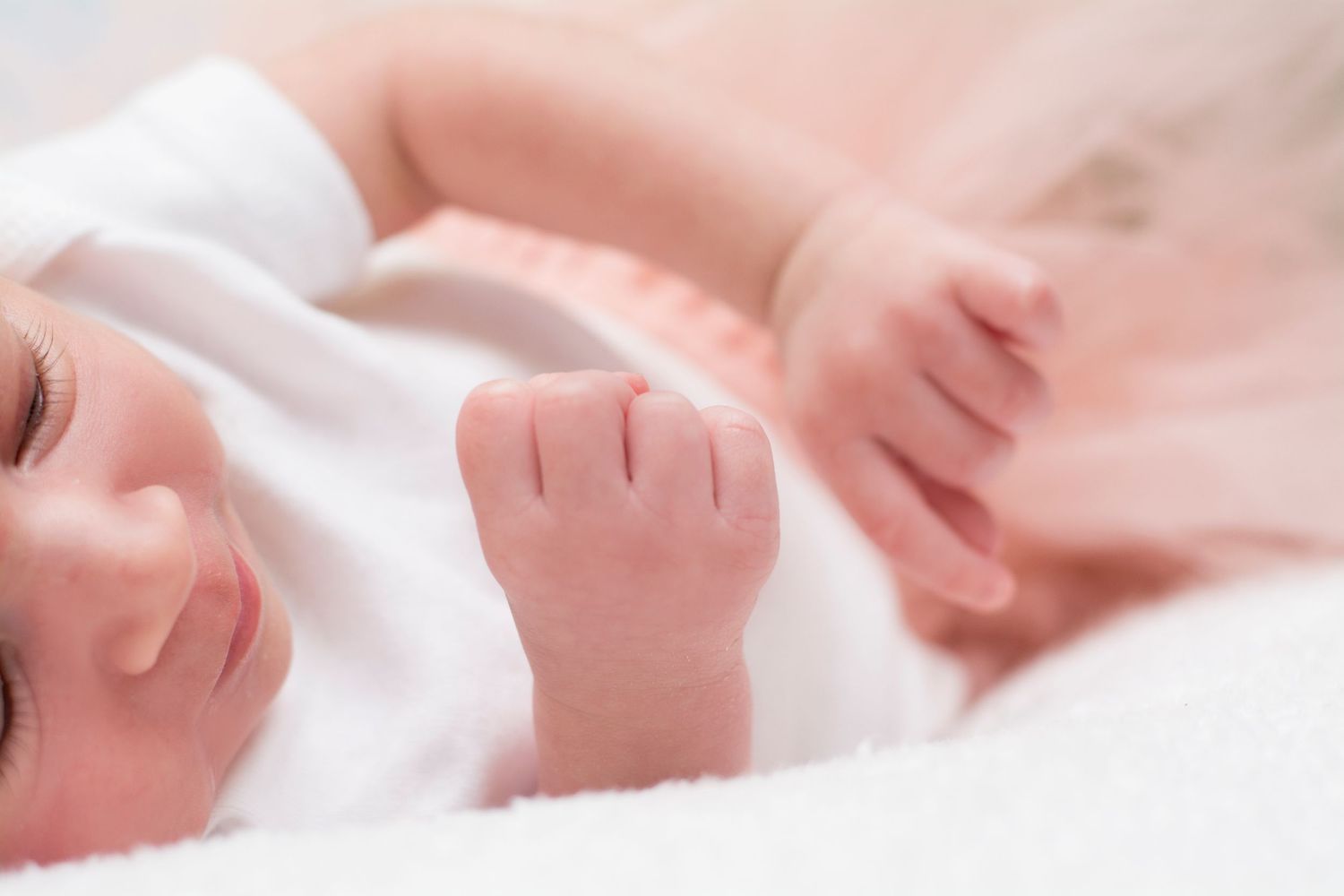 Peaceful sleeping newborn in soft white blankets.