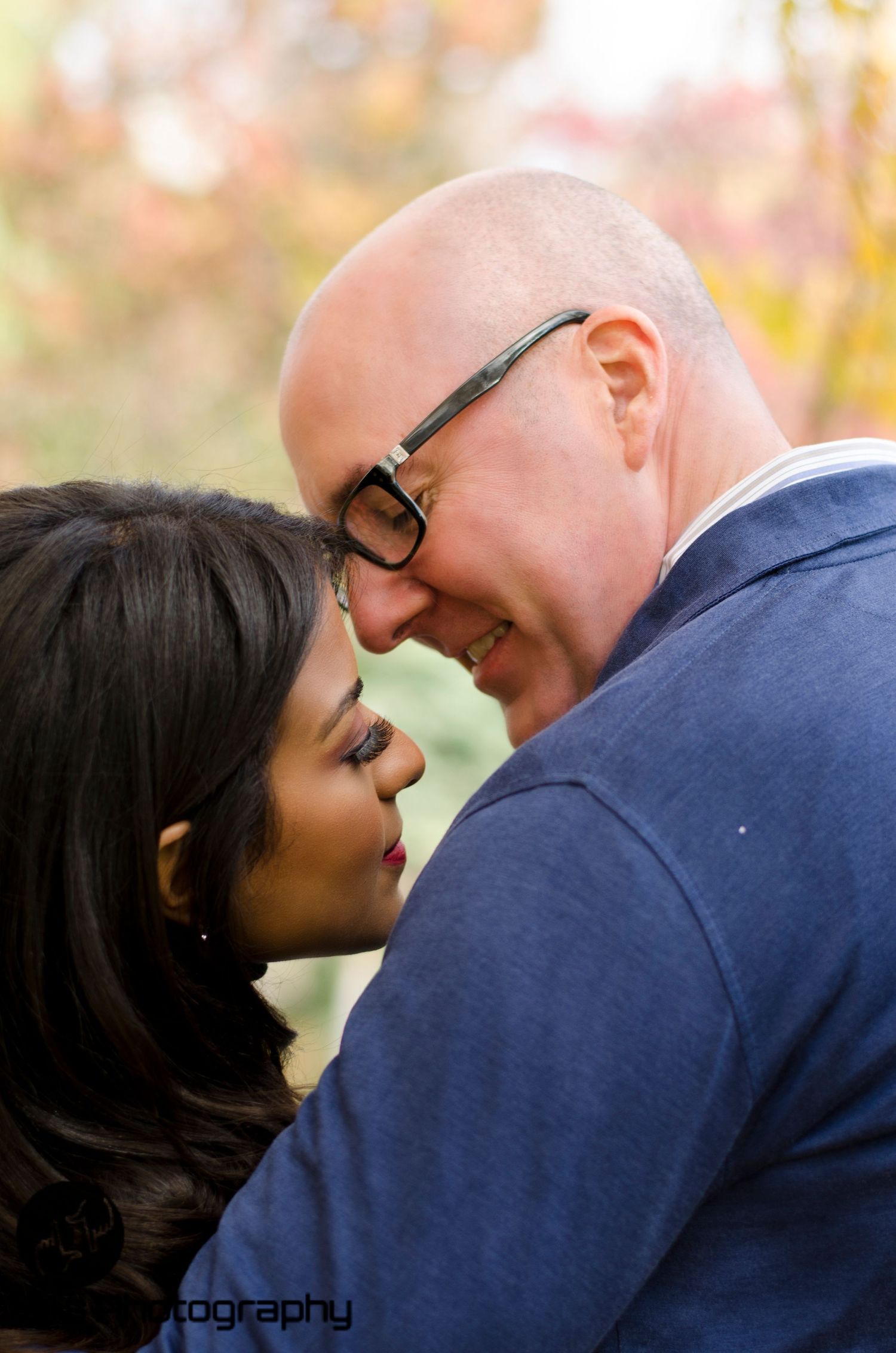 A couple shares an intimate close-up moment outdoors in autumn.