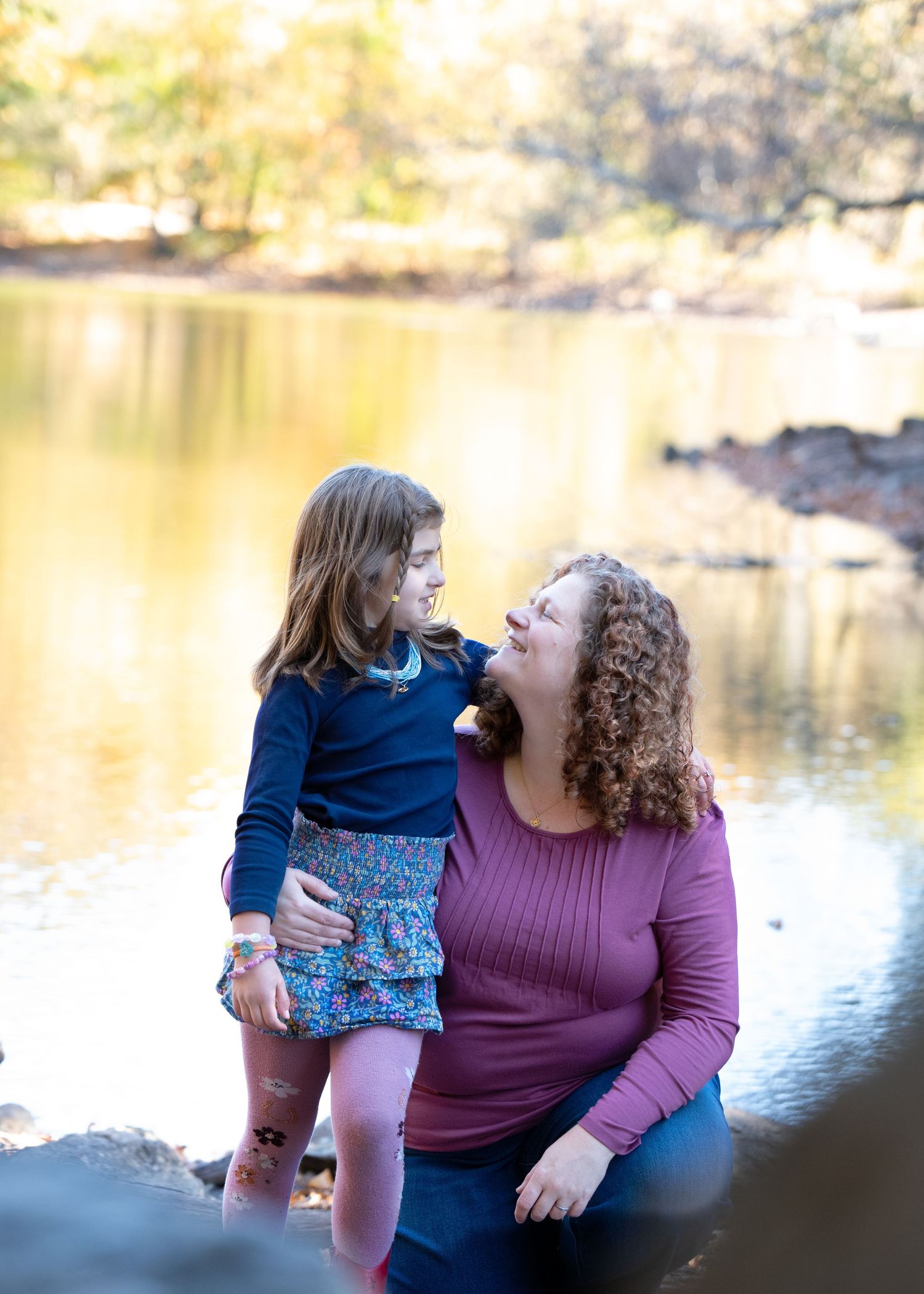 An intimate portrait of two people sharing a sweet moment by a sunlit lake.
