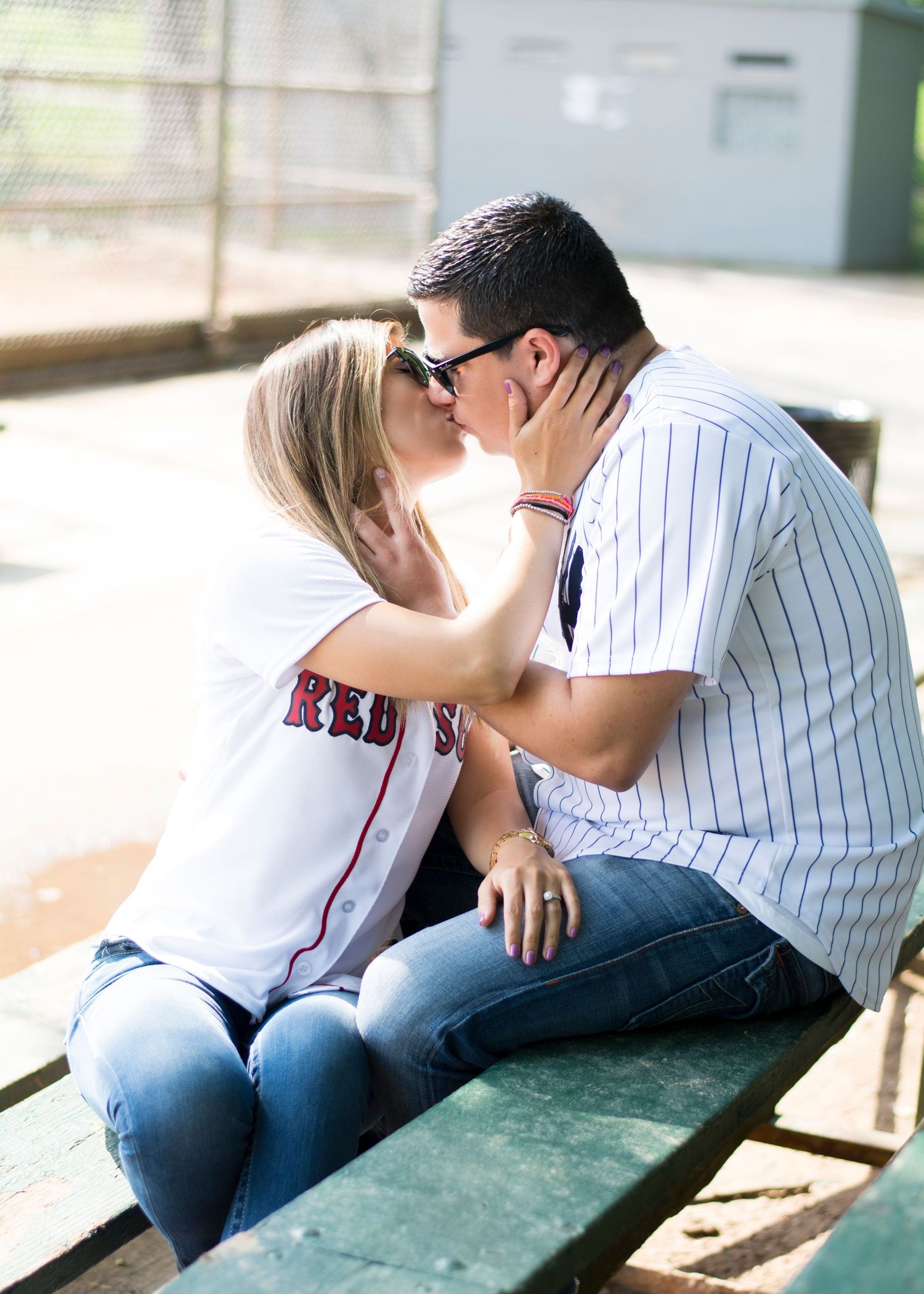 A couple shares a romantic kiss while sitting on wooden bleachers.