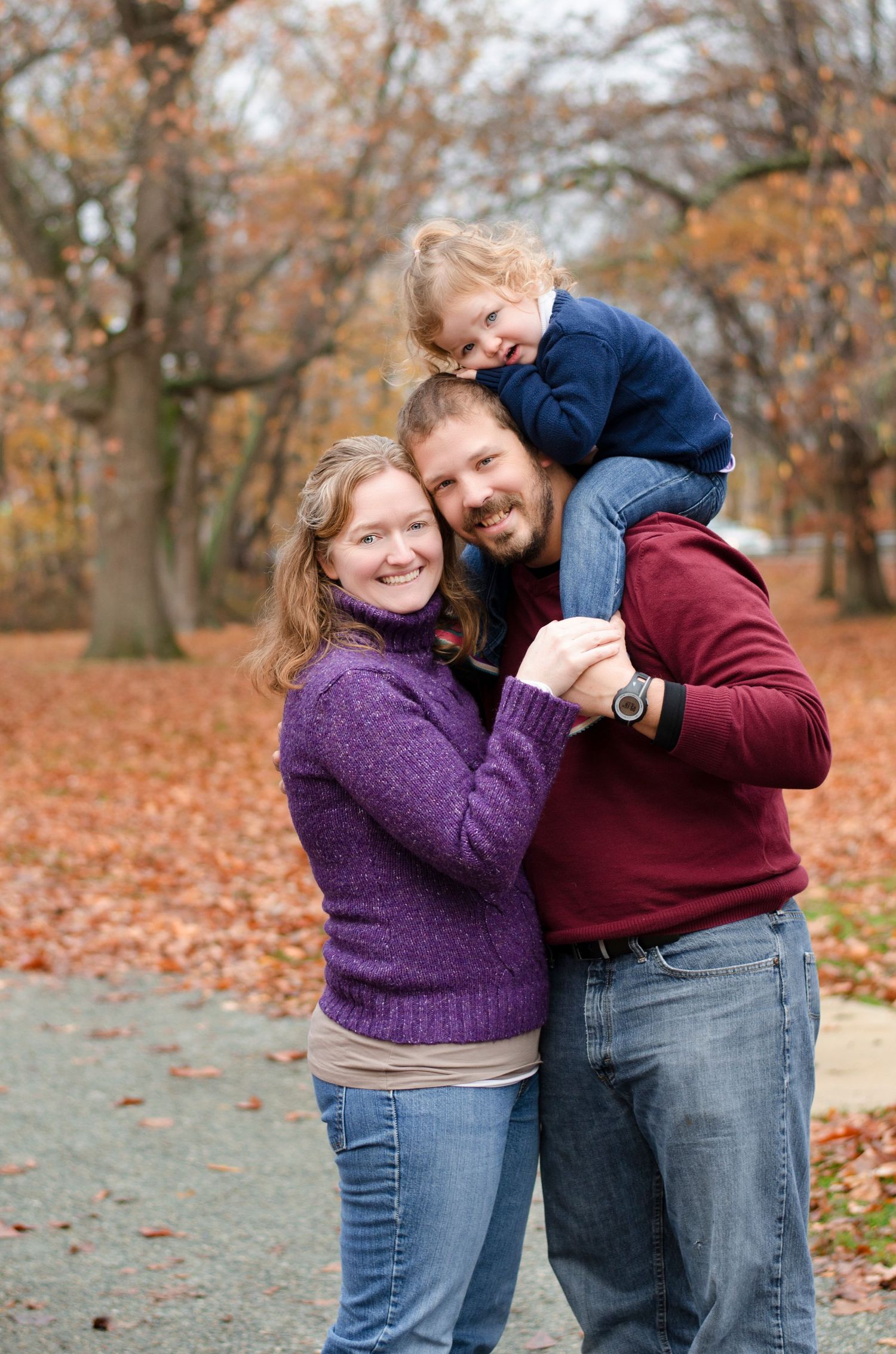 A happy group poses together on a path covered in fallen autumn leaves.