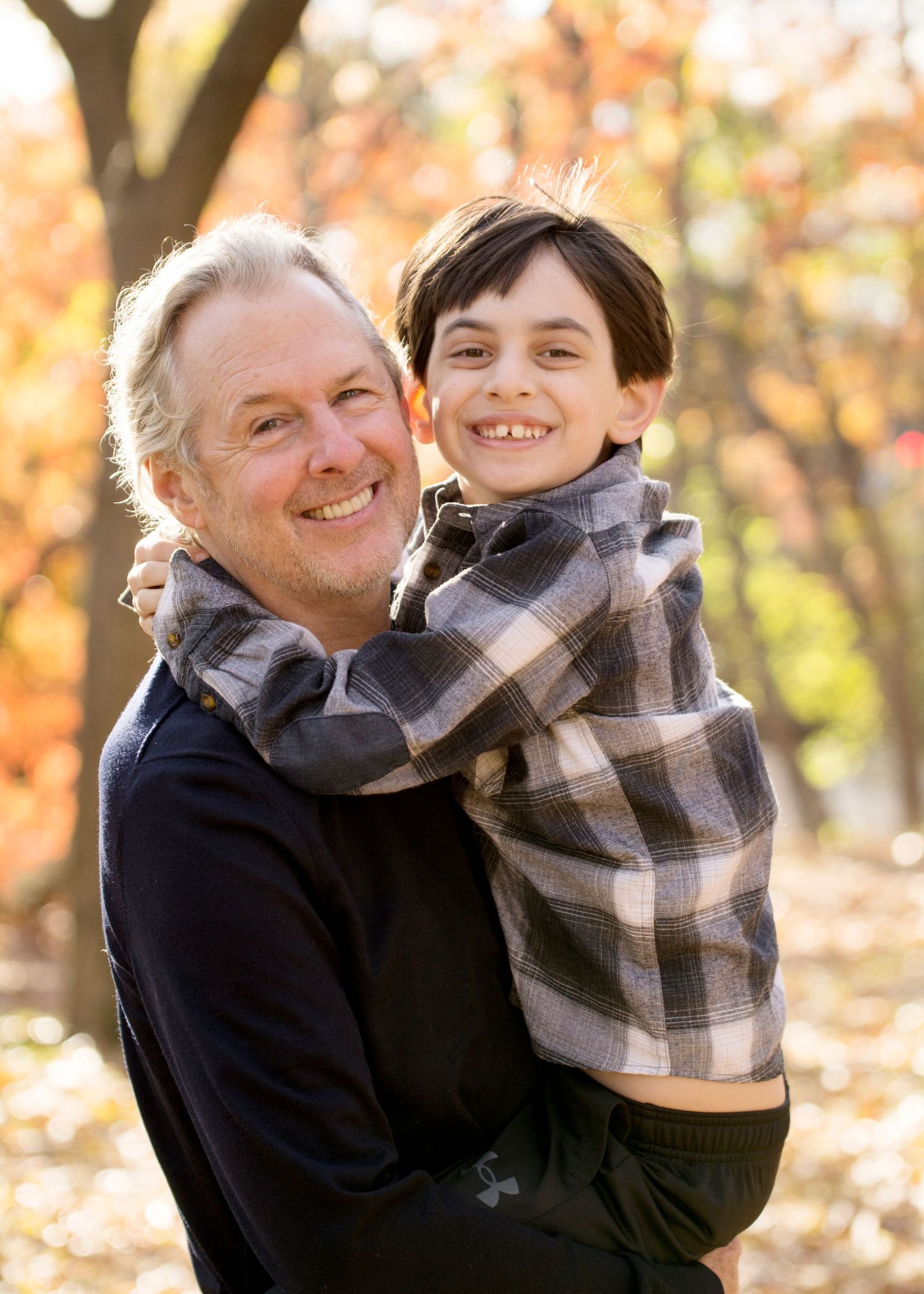 Heartwarming moment shared between two people wearing plaid against autumn backdrop.