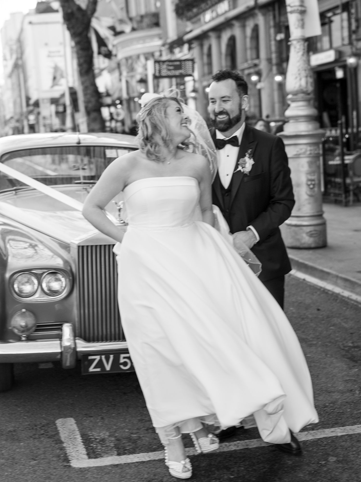 Black and white photo of couple kissing beside vintage Rolls Royce in Dublin.