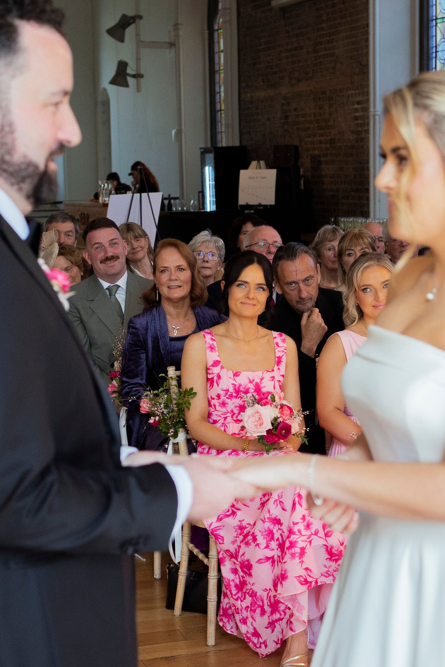 Wedding guests watch attentively as bride and groom exchange vows in a historic church ceremony.