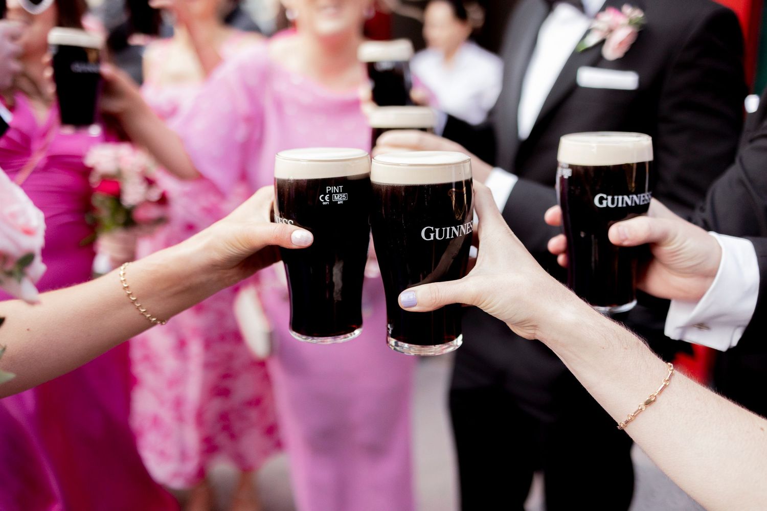 Wedding guests toast with Guinness pints at reception celebration.