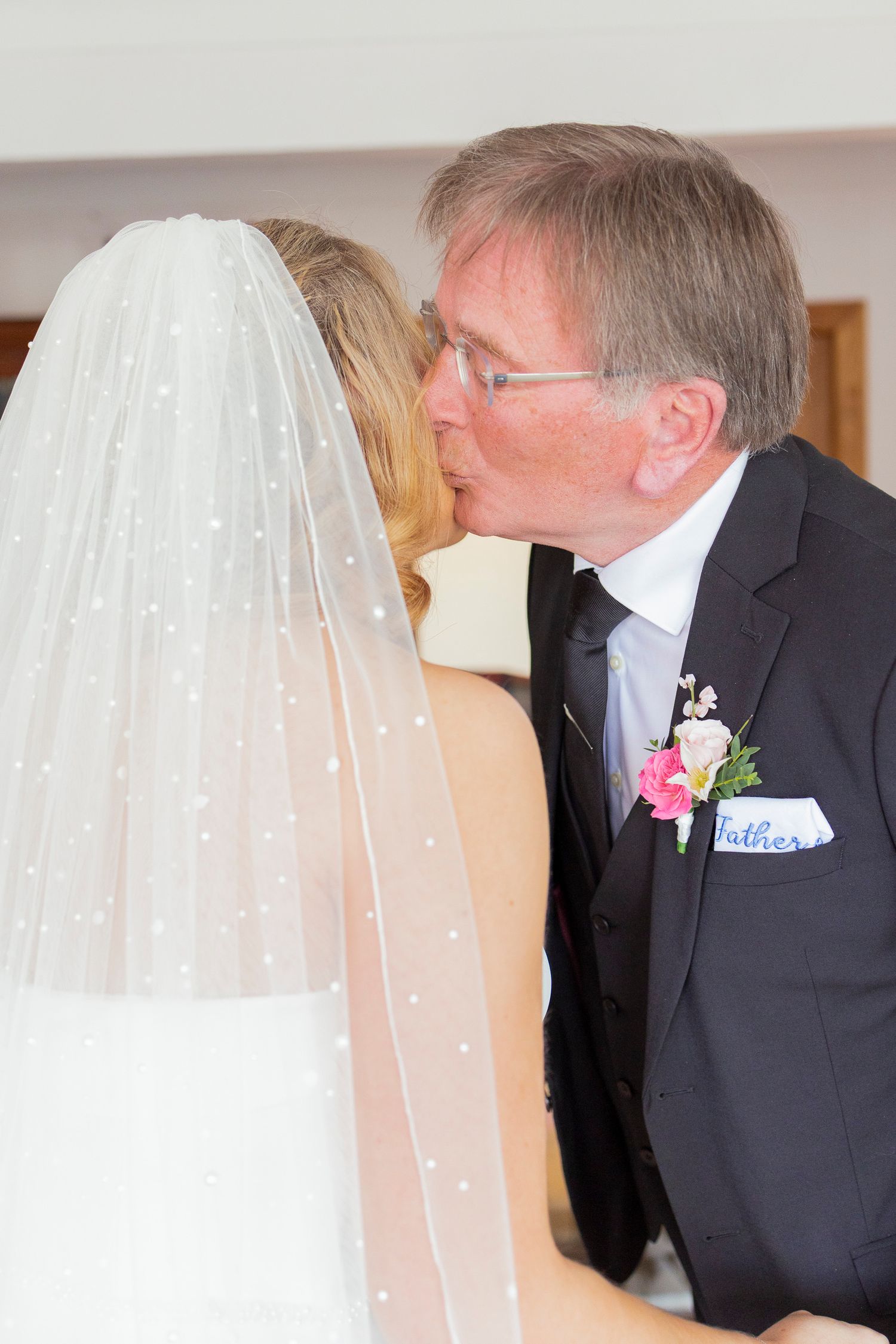 Father of the bride kissing his daughter on the cheek before the wedding ceremony.