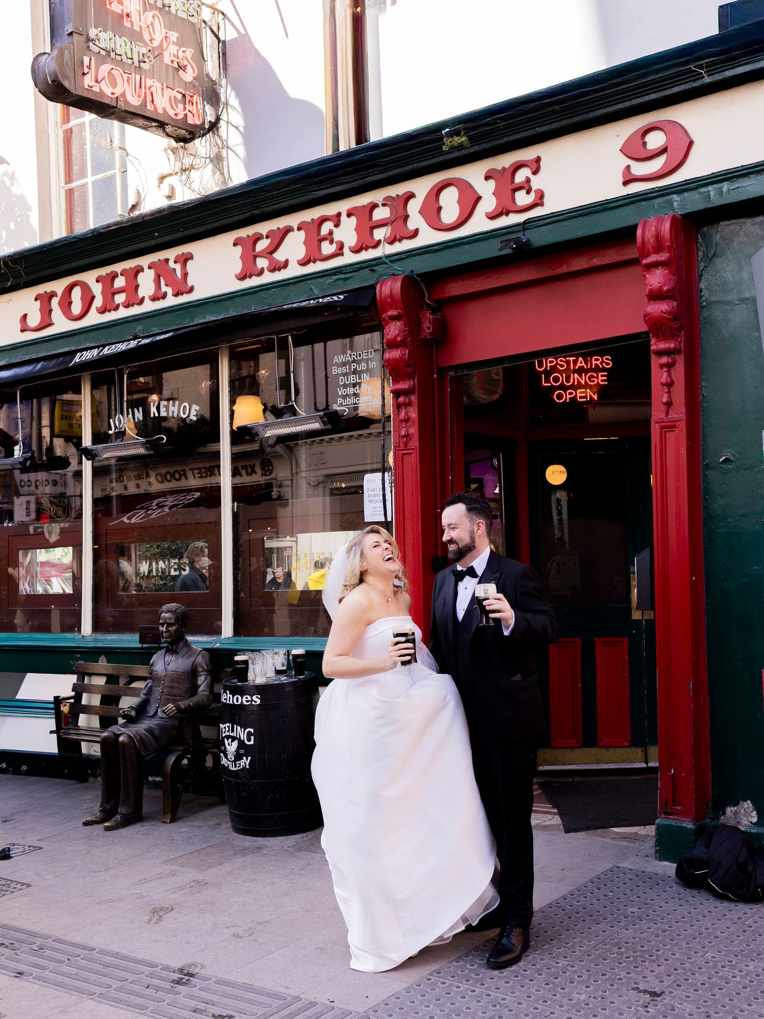 Newlyweds pose and laugh outside John Kehoe pub on a Dublin street after their wedding ceremony.