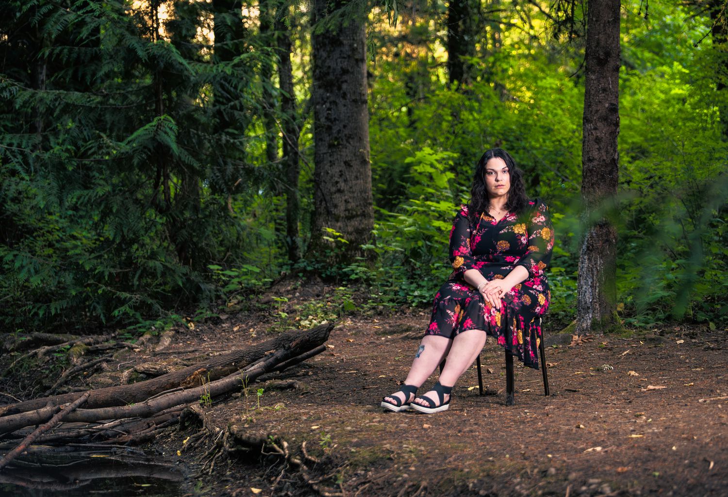 Editorial portrait of a woman in a floral dress seated among forest roots — Ground Glass Photography, Kent WA