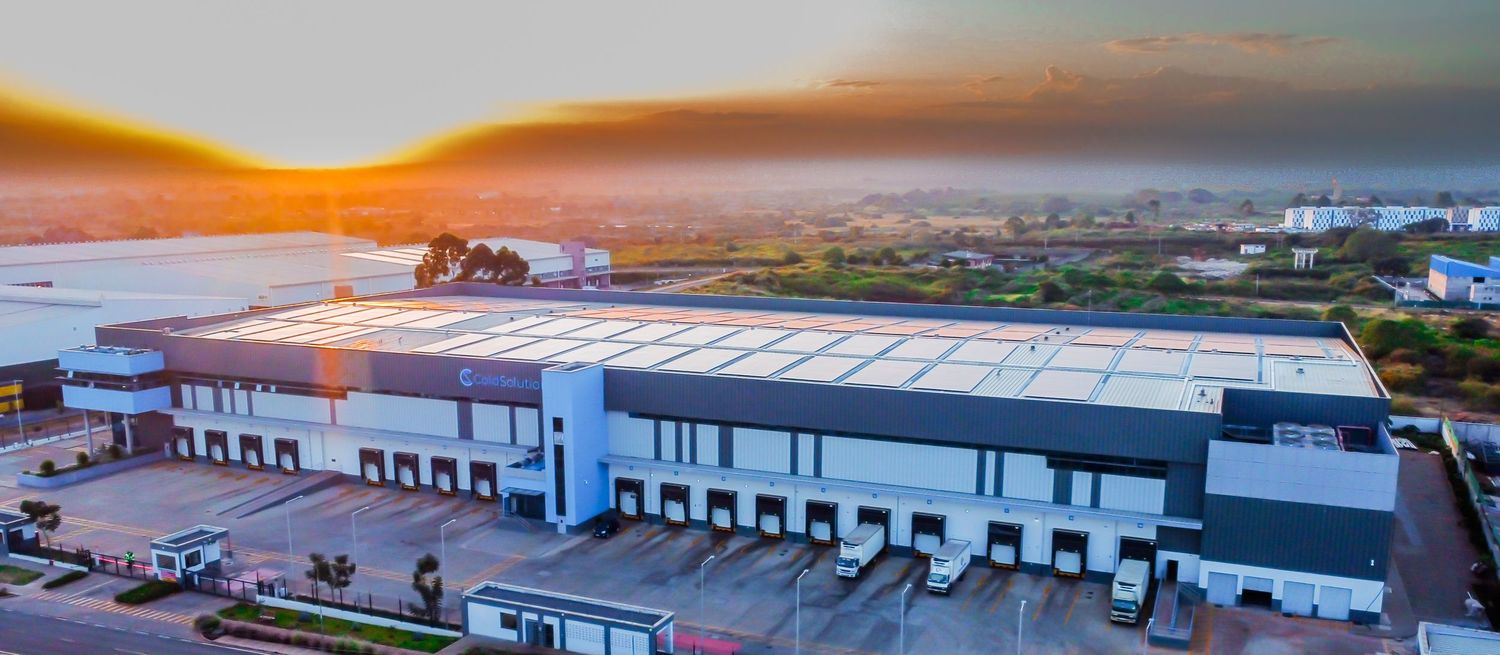 Aerial drone photograph of a large modern industrial warehouse and logistics distribution center with loading docks during a vibrant golden