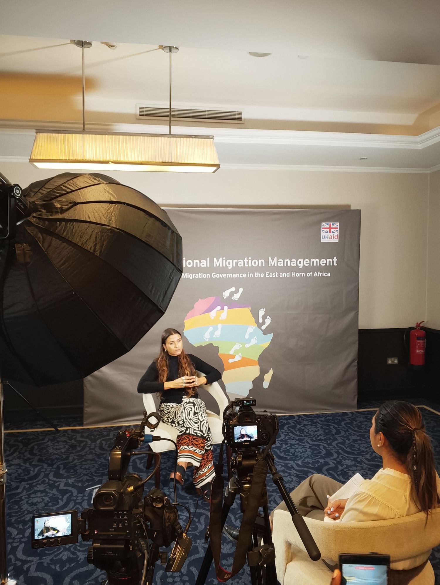 Behind-the-scenes of a corporate documentary video shoot featuring a multi-camera interview setup, a large softbox studio light.