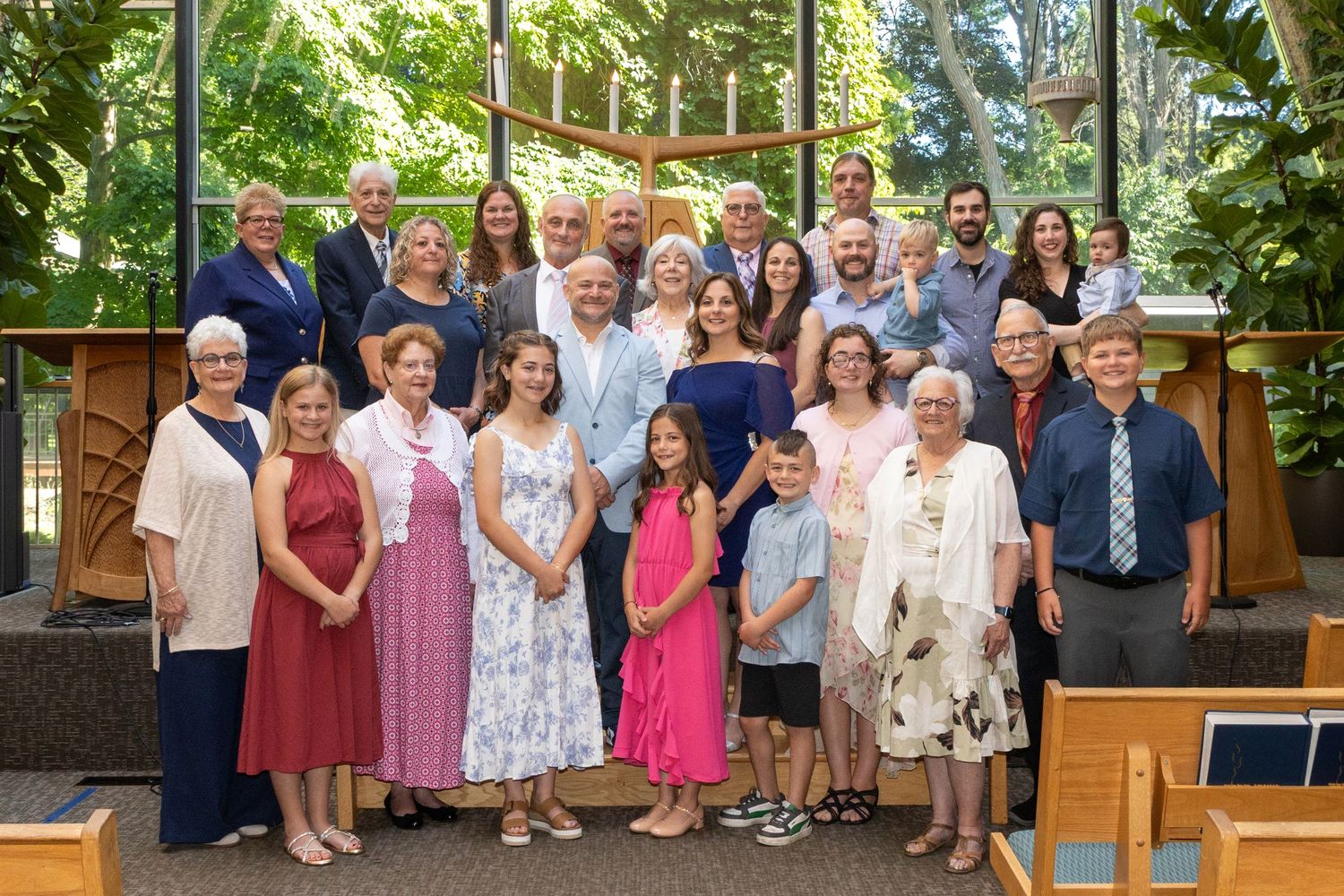 Large family group posing together inside a sunlit temple during a special celebration.