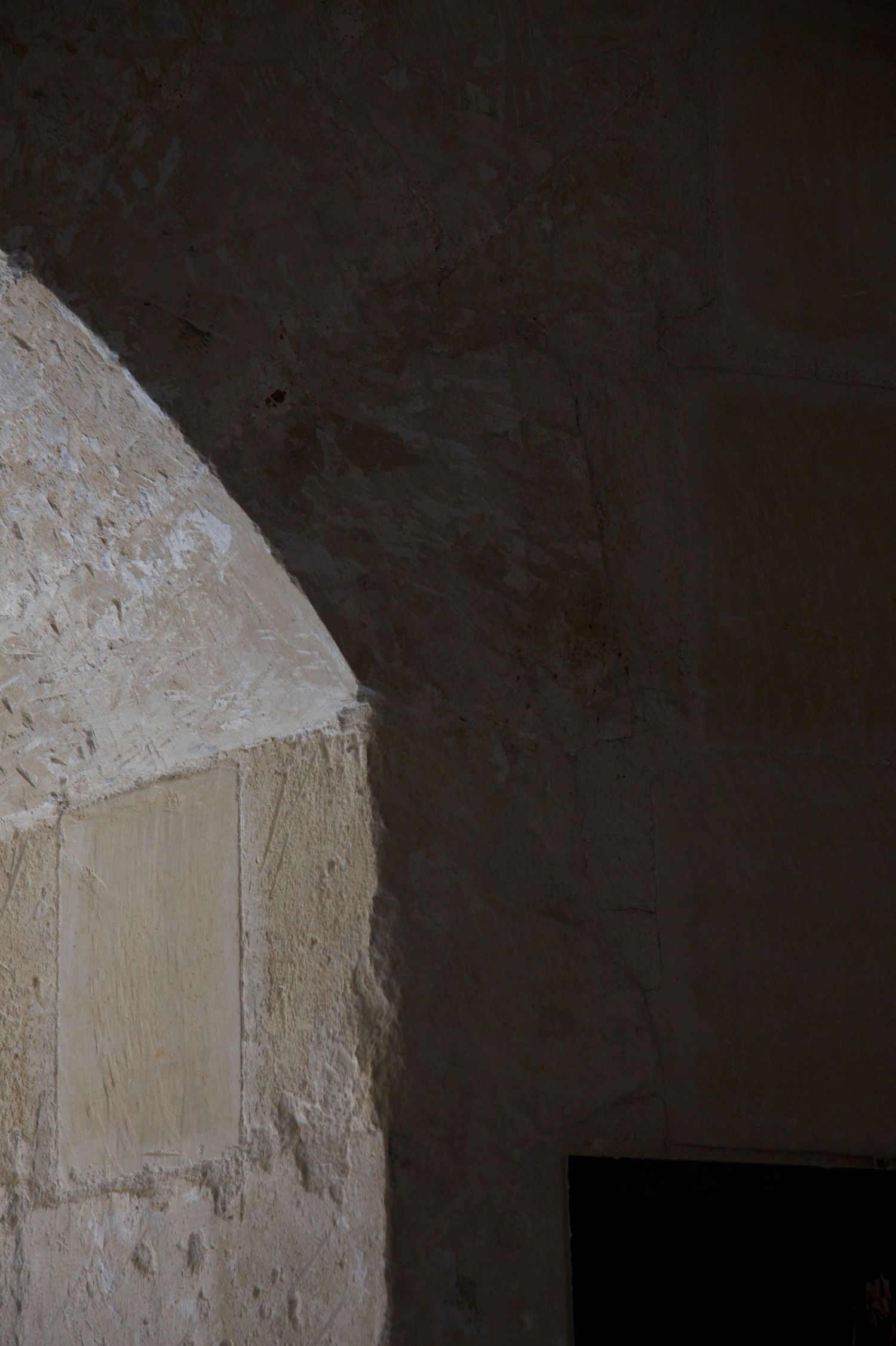 Close-up of a stone archway with rough textured walls in dim lighting.
