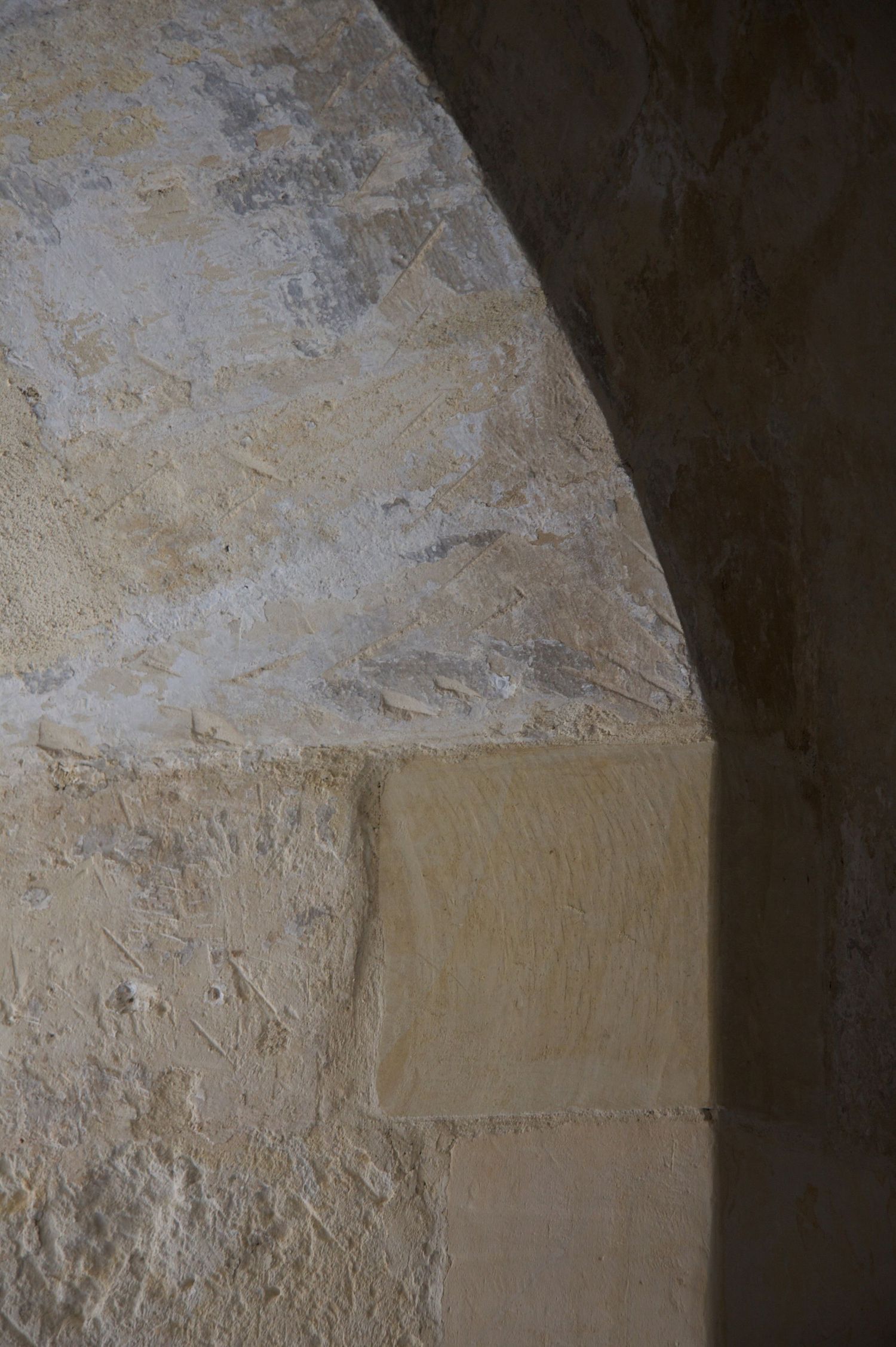Close-up of a weathered stone archway with textured limestone blocks in natural light.