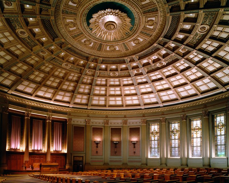 Ornate domed auditorium ceiling with gold details, arched windows, and stage area.