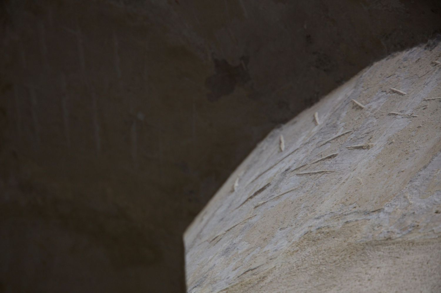 Close-up of carved leaf detail on weathered stone arch in ancient historic building interior.