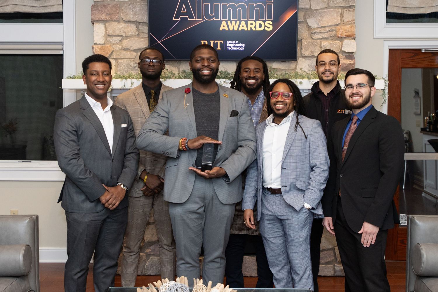 Group of young men posing with alumni award trophy at RIT ceremony.