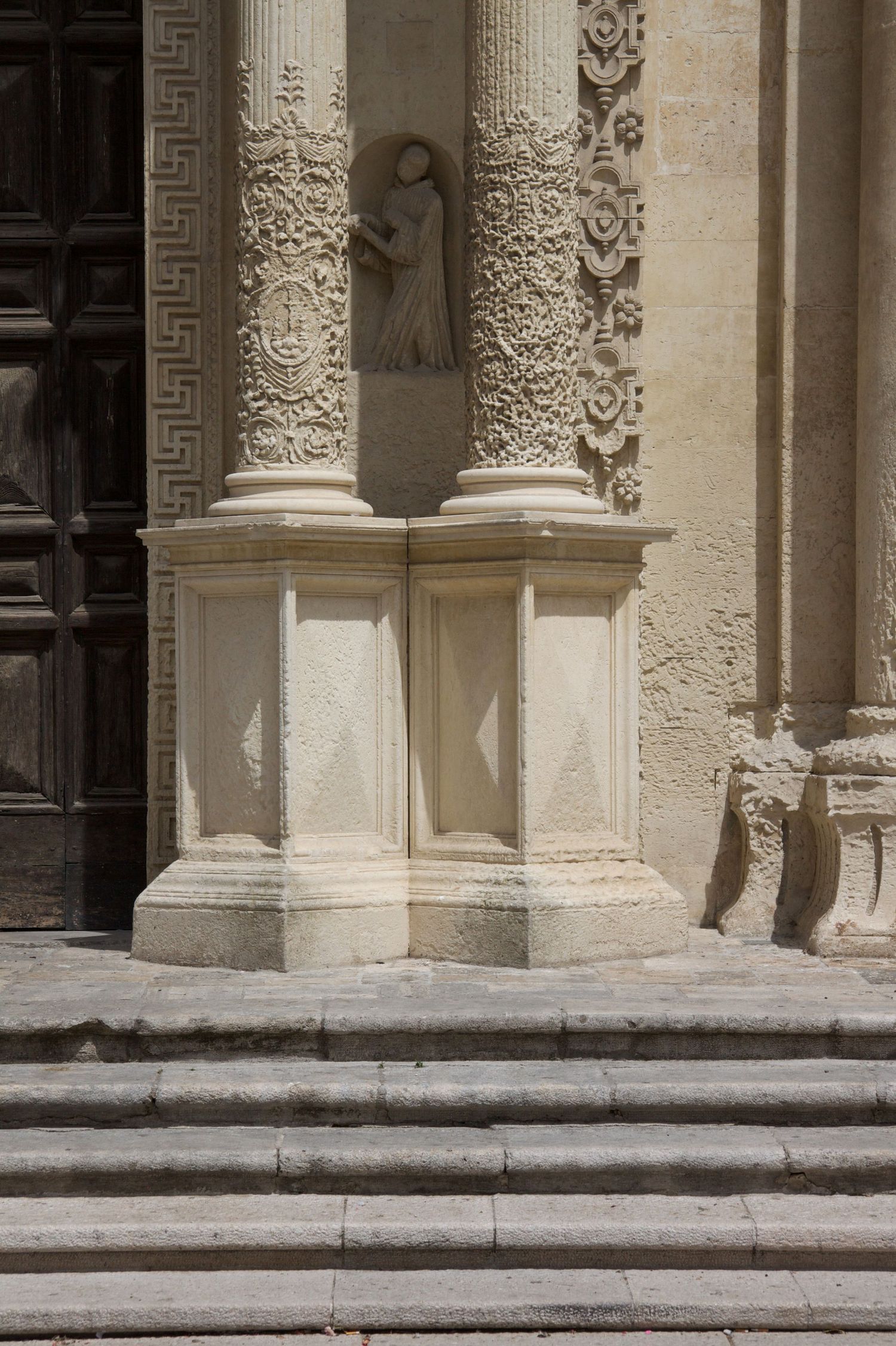 Ornate carved stone columns with decorative relief work flanking cathedral entrance steps.