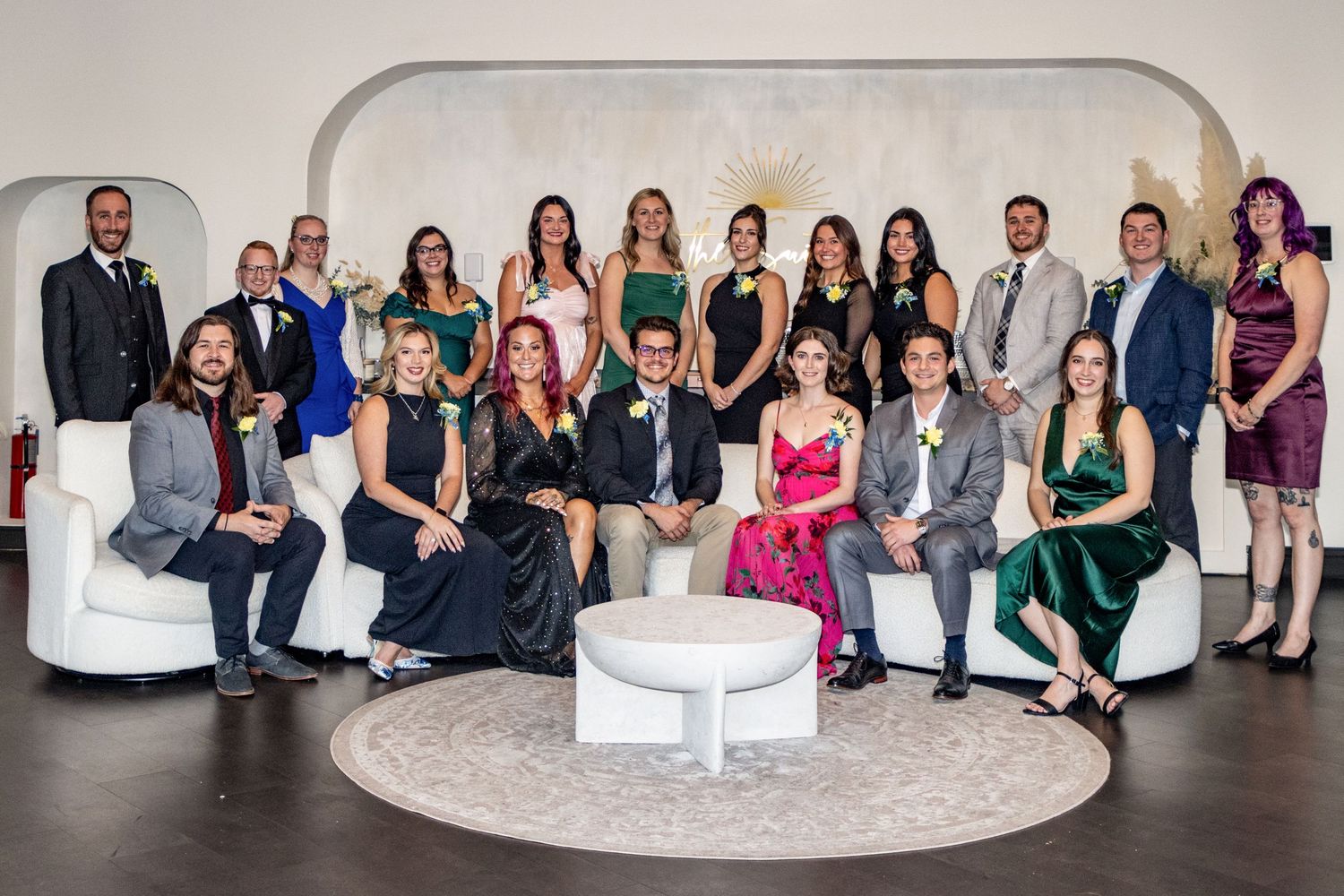 Formally dressed group of young professionals posing together at an upscale gala celebration.